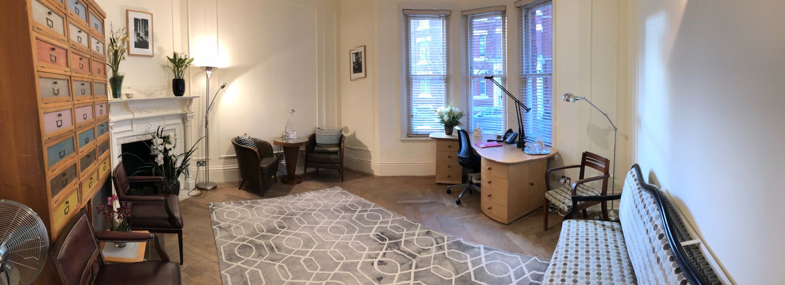 Bright consulting room with comfortable seating for meetings at Wilbraham Place Practice.