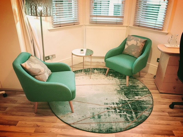 Cozy consulting room with green chairs for intimate meetings at Wilbraham Place Practice.