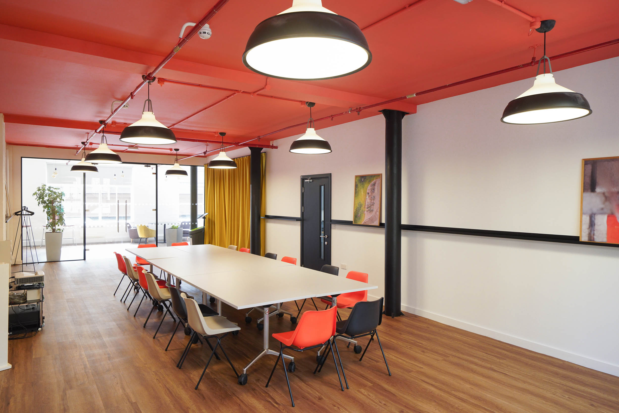 Modern meeting space at The Hive, London Bridge with colorful chairs and bright red ceiling.