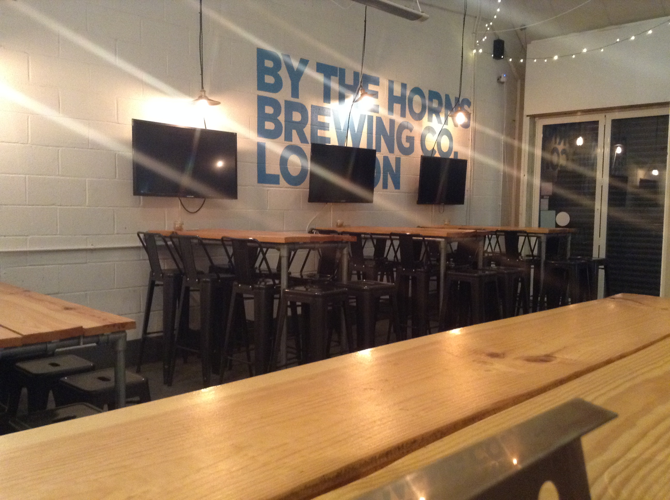 Modern Taproom Bar at By The Horns Brewing Co. with wooden tables for events and meetings.