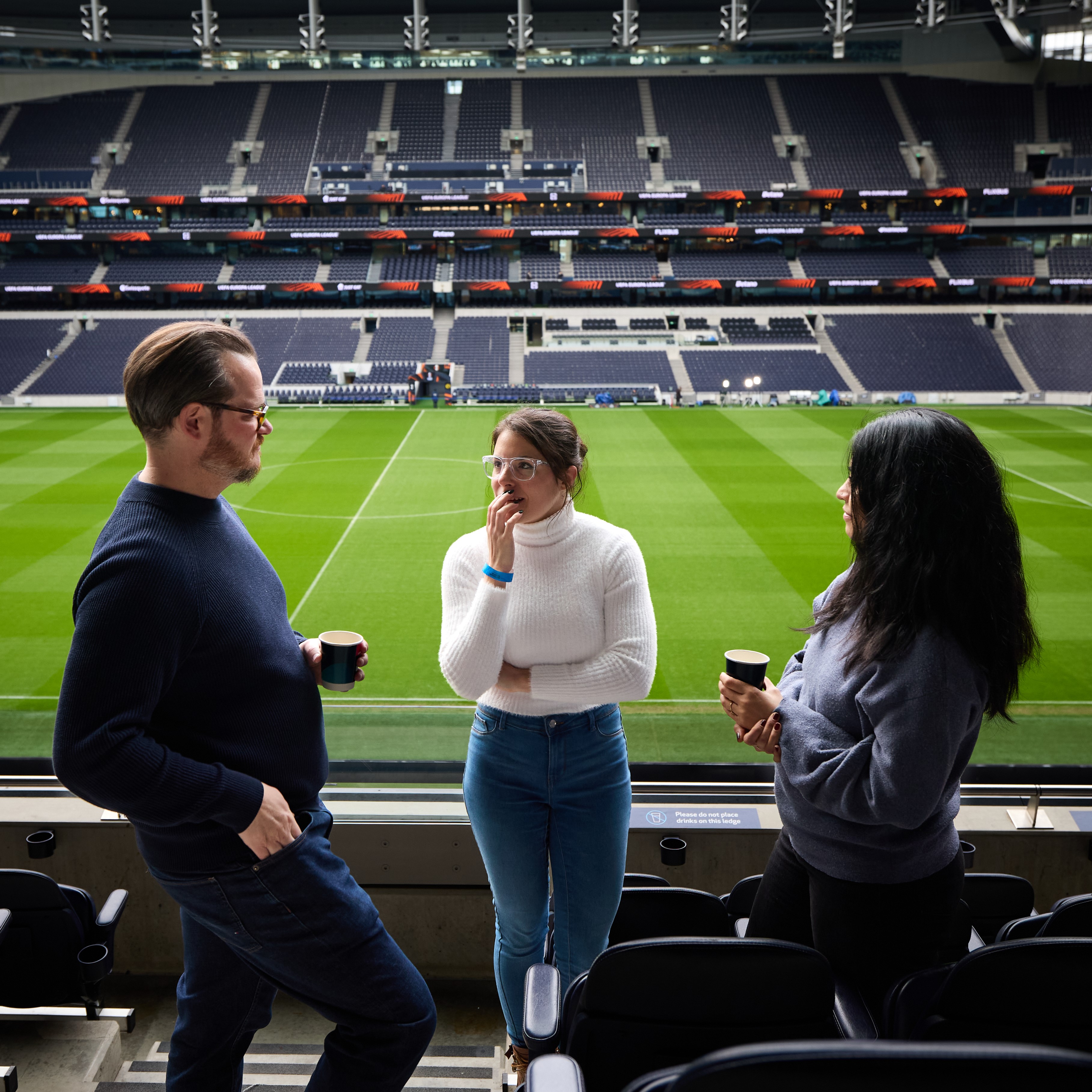 "Engaged professionals discuss strategy at Tottenham Hotspur Stadium, ideal for events."