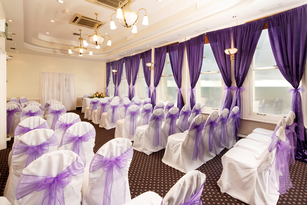 Coast View 1 event space with white chairs and purple sashes, perfect for weddings.