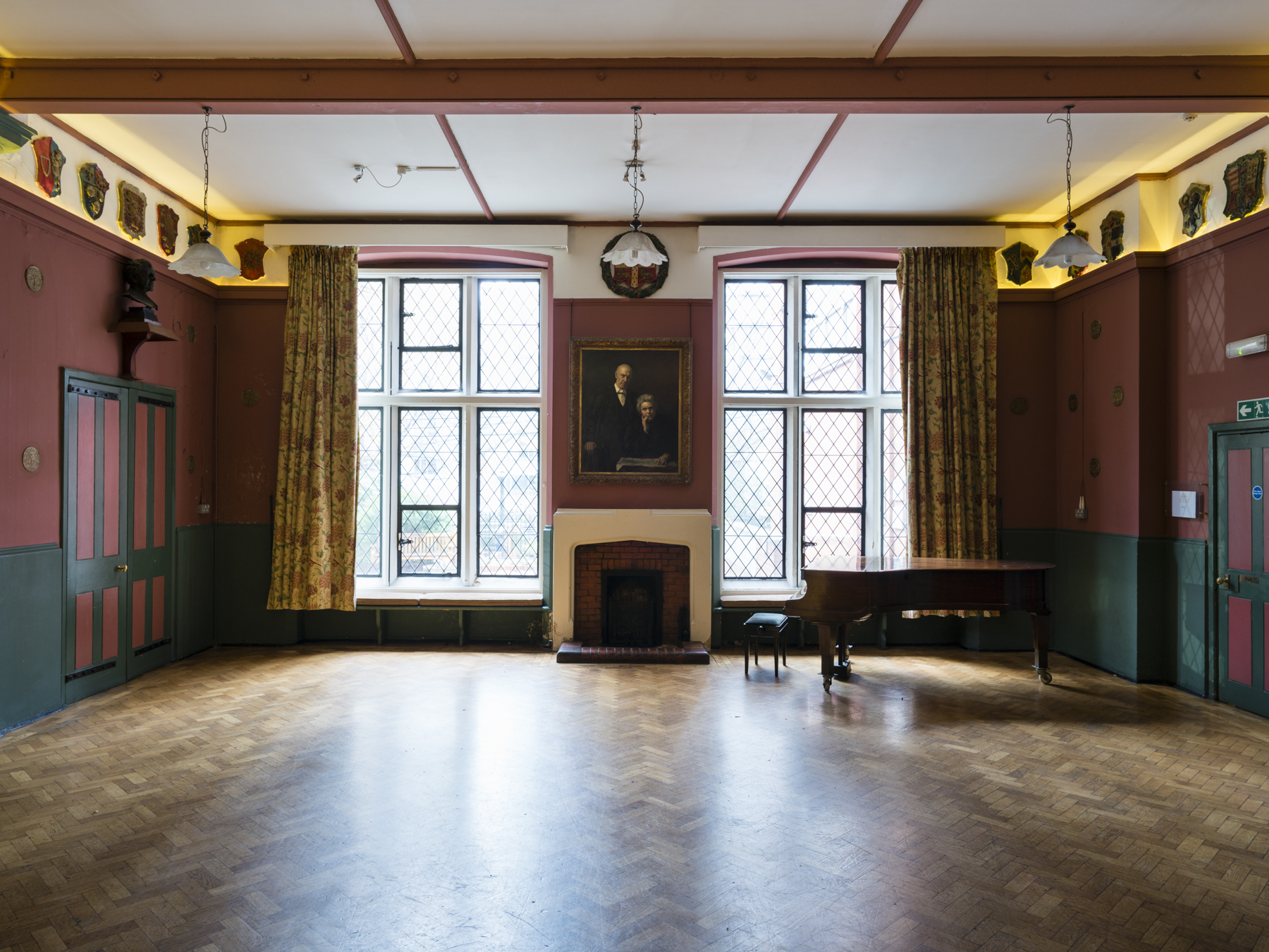 Lecture Hall at Toynbee Hall with grand piano, ideal for meetings and events.