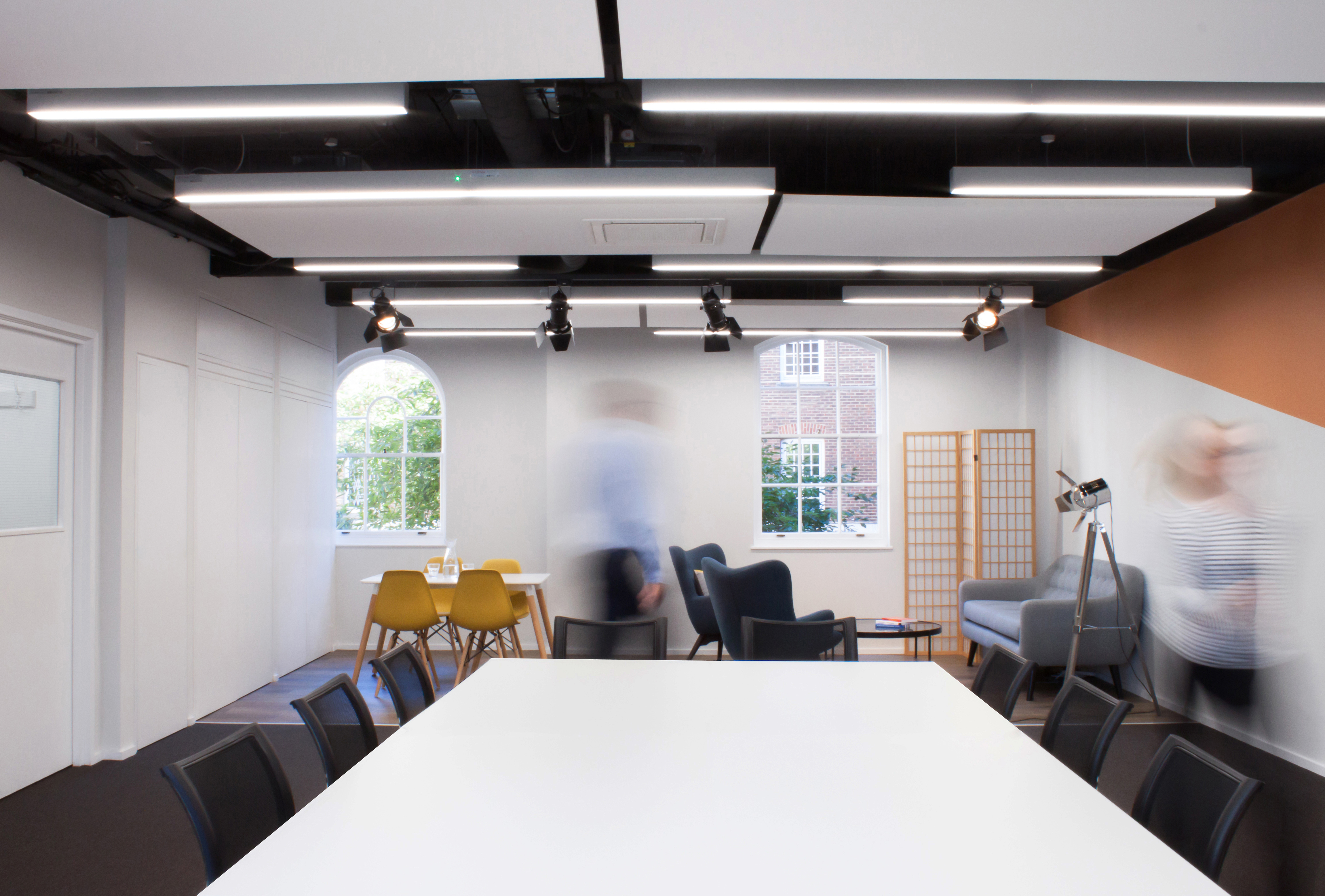 Modern meeting room with large white table, ideal for workshops and brainstorming sessions.