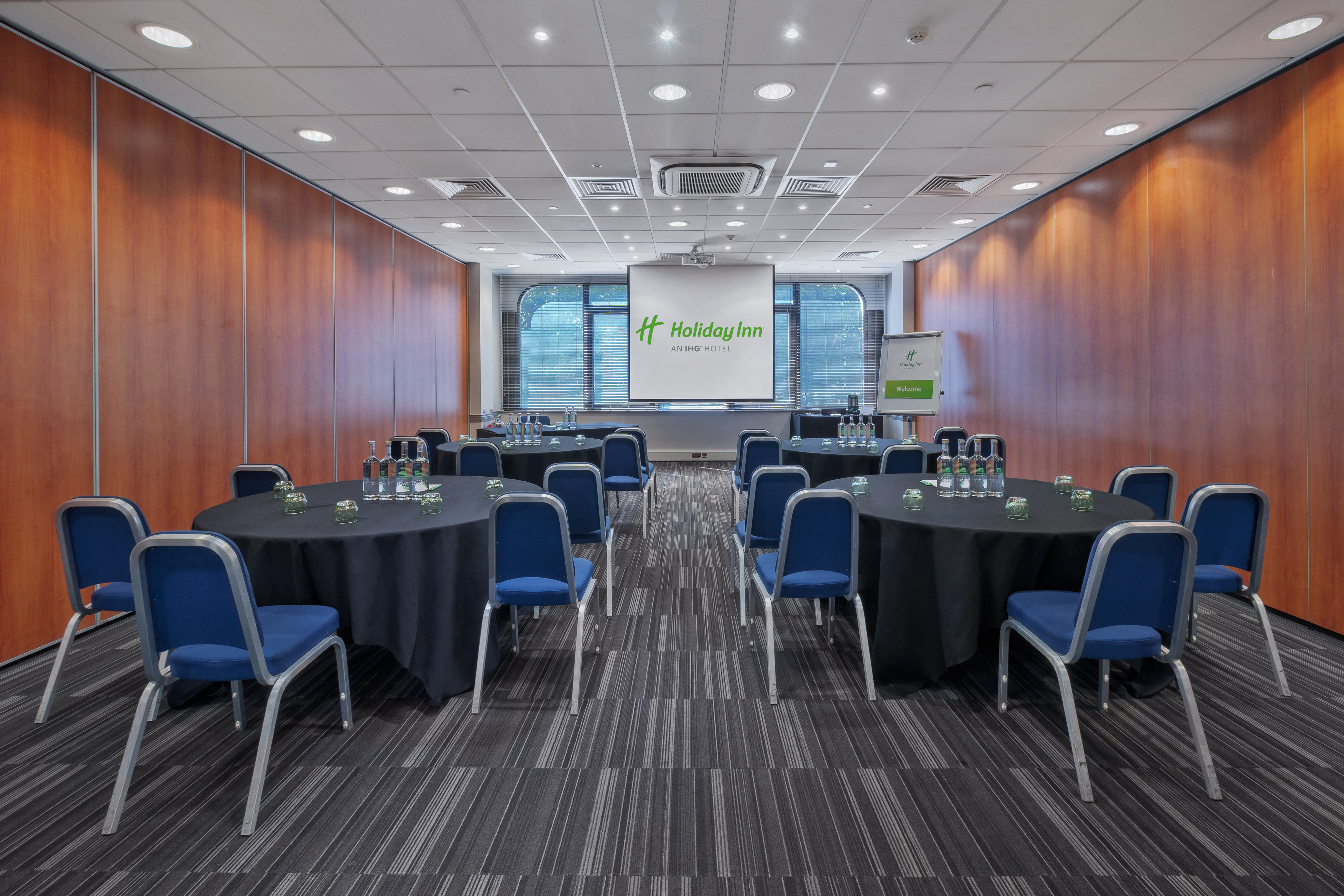 Modern meeting room with round tables at Holiday Inn Kensington for corporate events.
