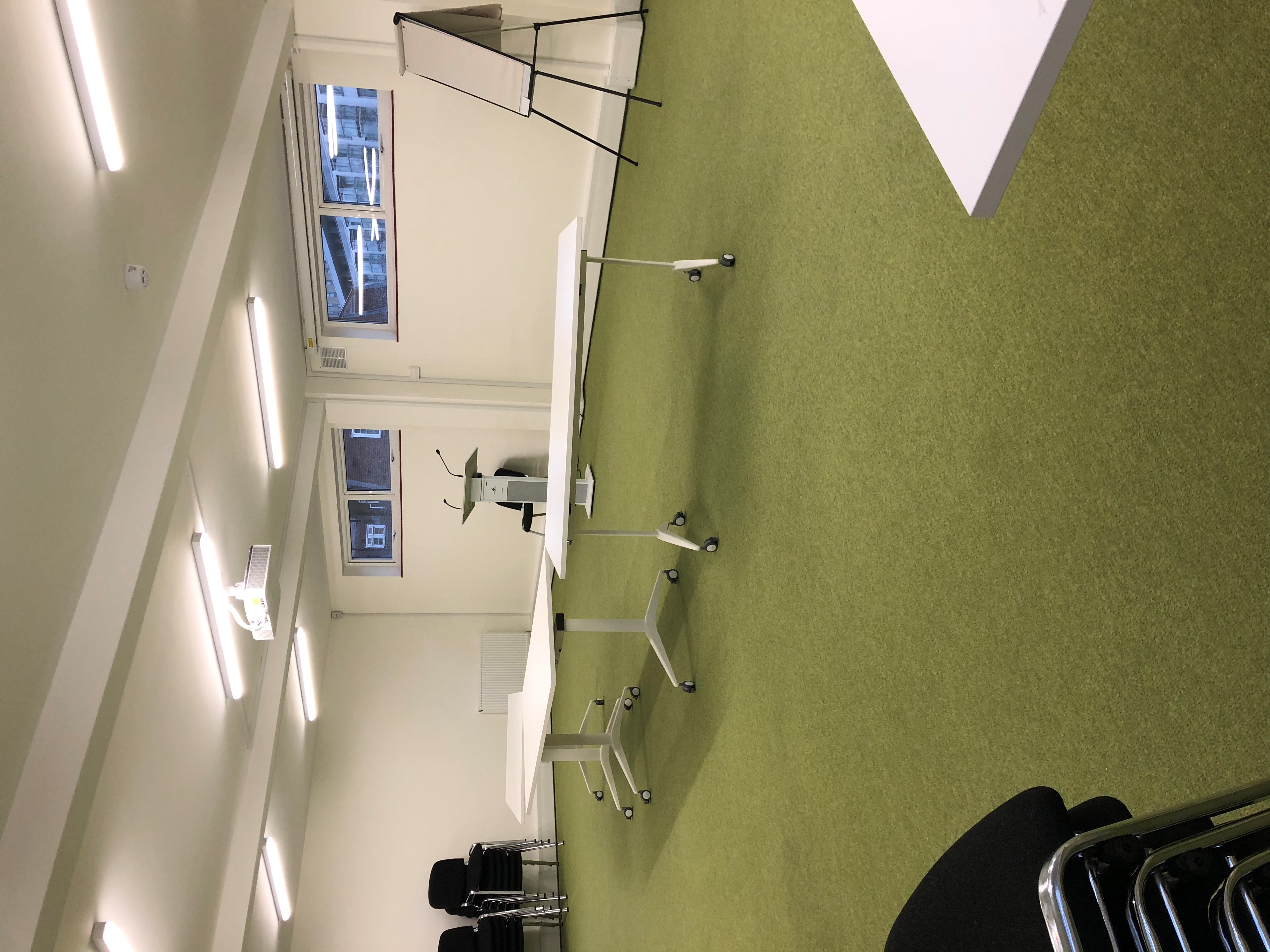 Flexible training room with mobile tables and green carpet for collaborative events.