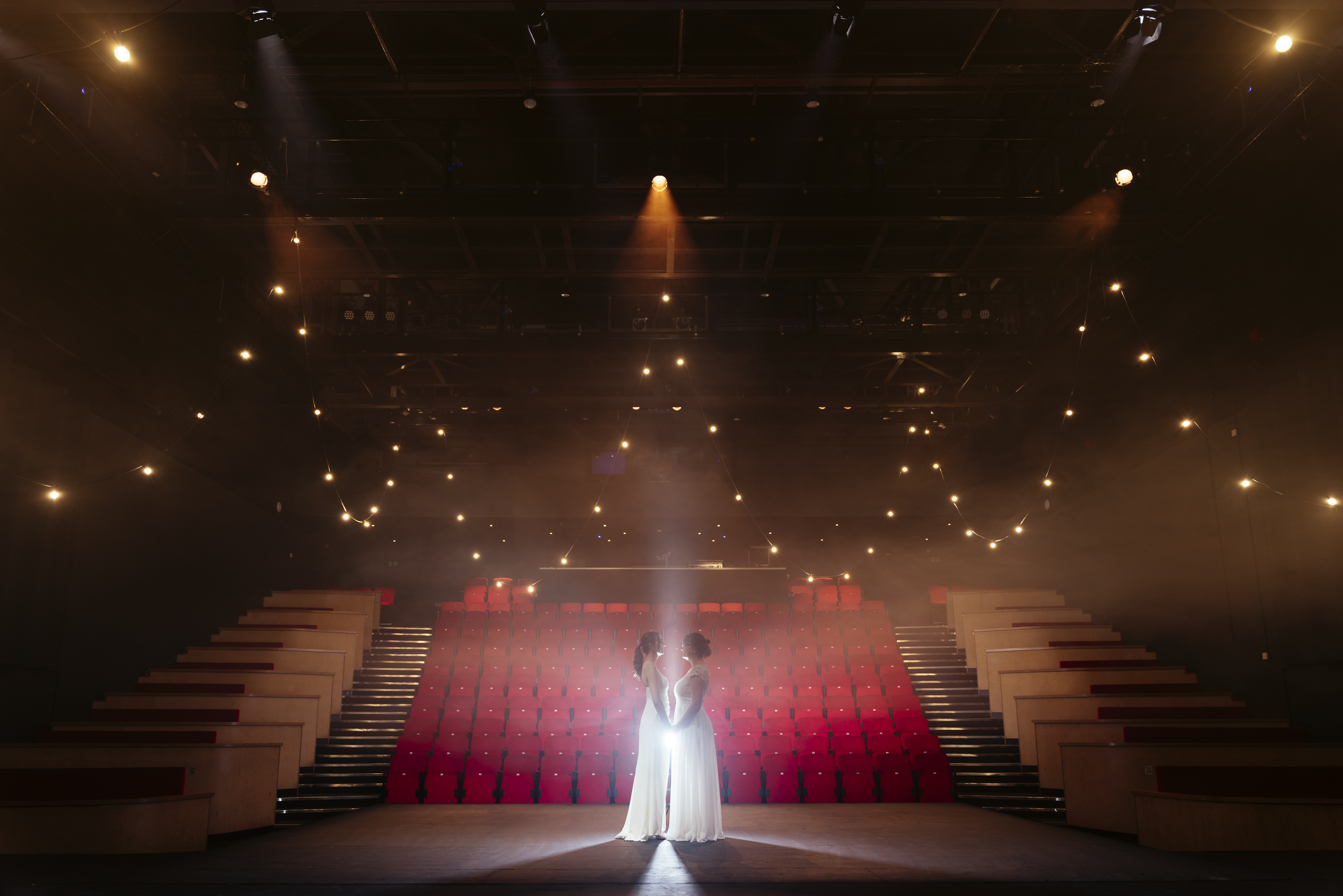 Event space with dramatic stage and red seating, ideal for presentations and performances.