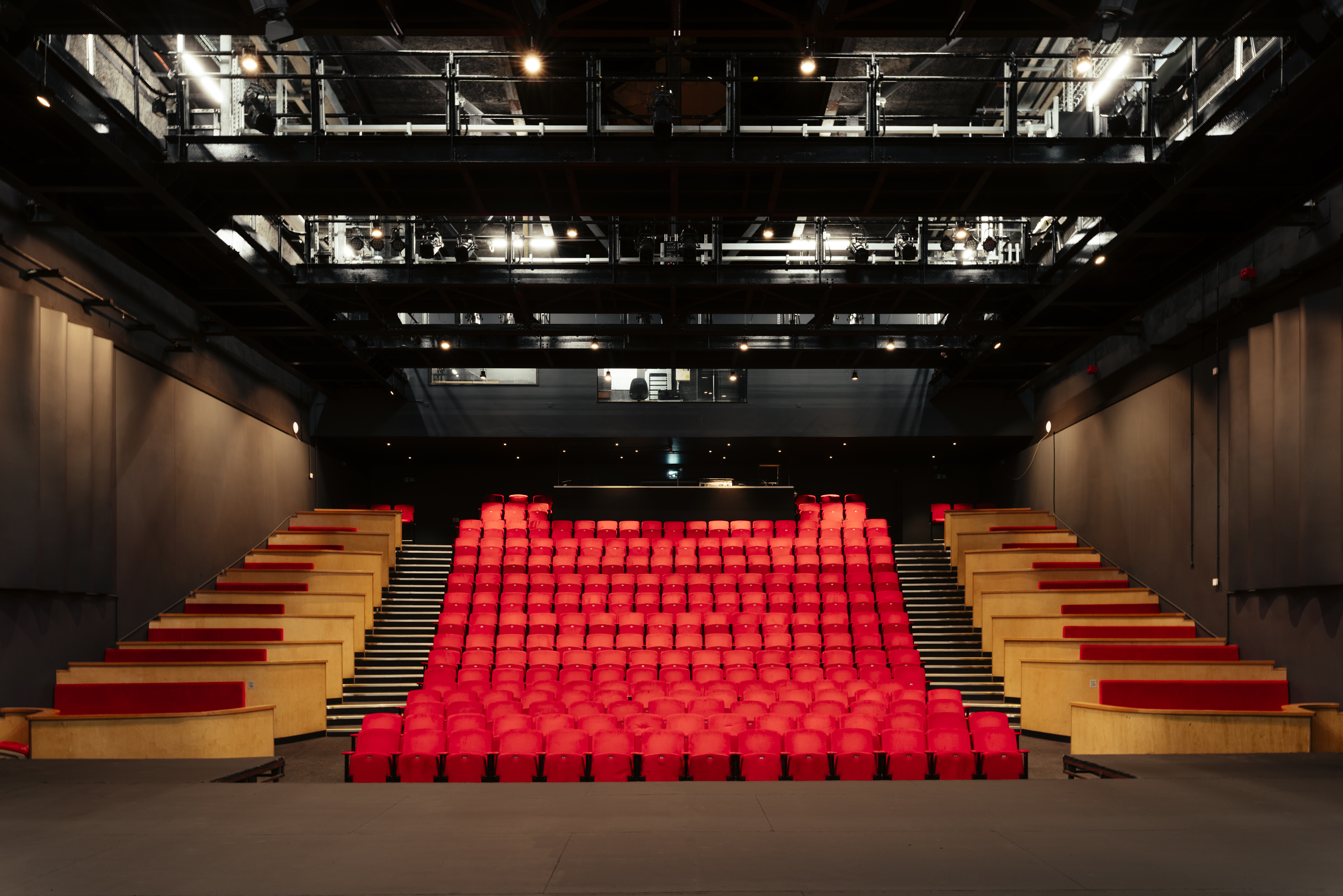 Modern auditorium with tiered red seating for versatile events at Contact Theatre.