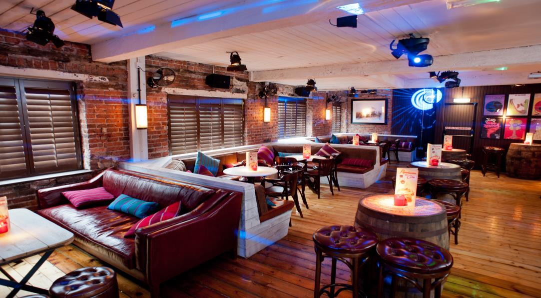 Stylish event space at El Atico, featuring cozy seating and vibrant lighting for gatherings.