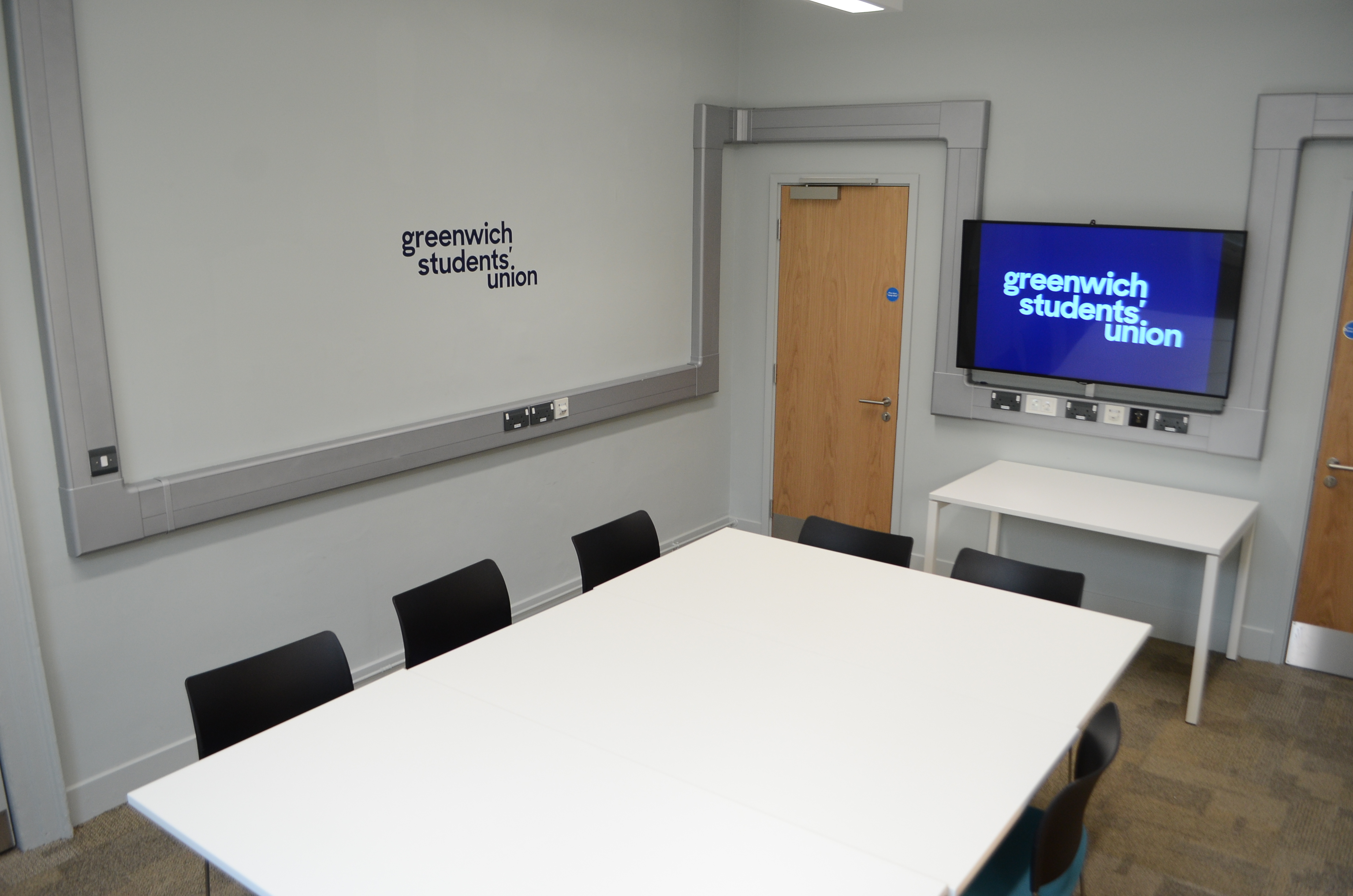 Modern meeting room with large white table, ideal for workshops and hybrid events.