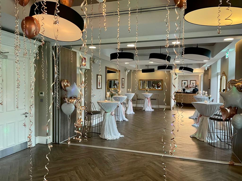 Elegant event space with cocktail tables and balloons for social gatherings.