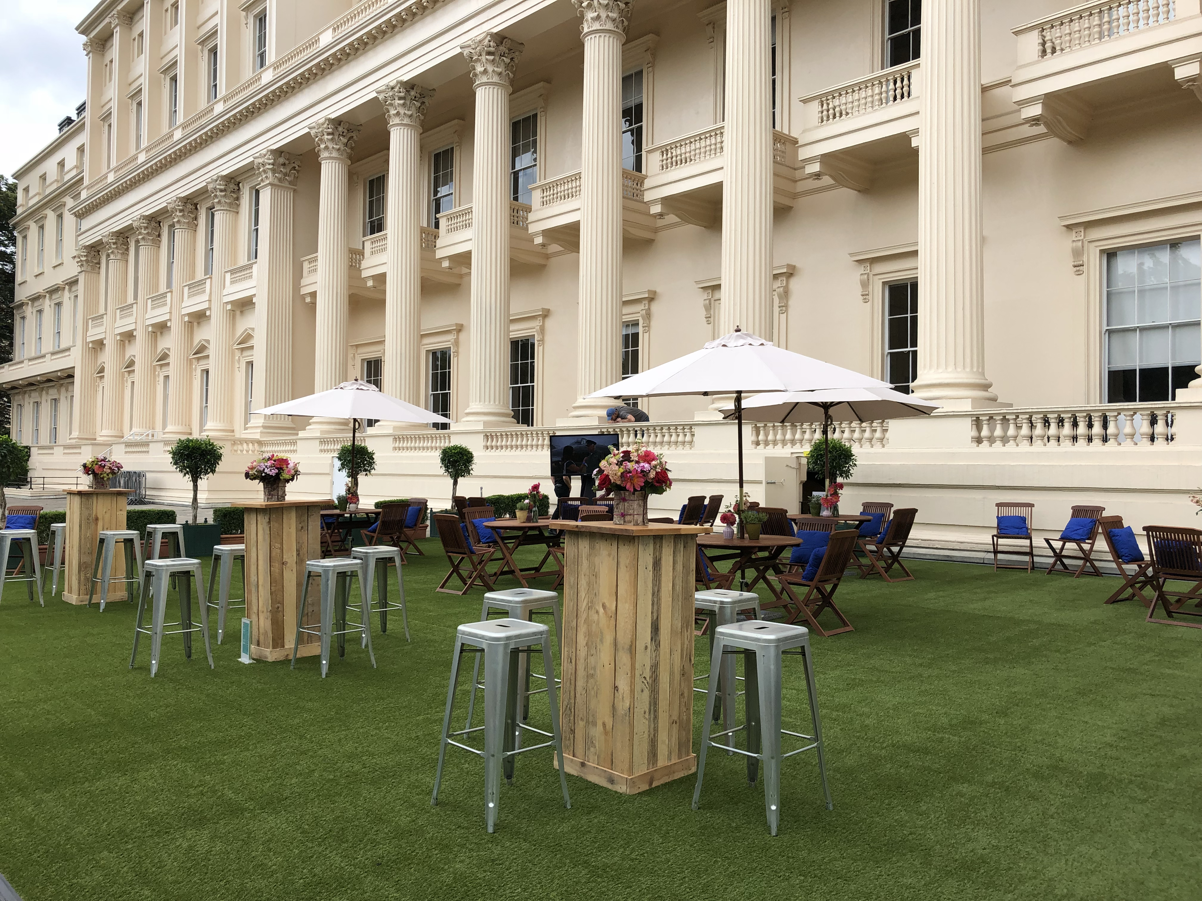 Elegant outdoor wedding venue with wooden bar tables and lush turf at Prince Philip House.