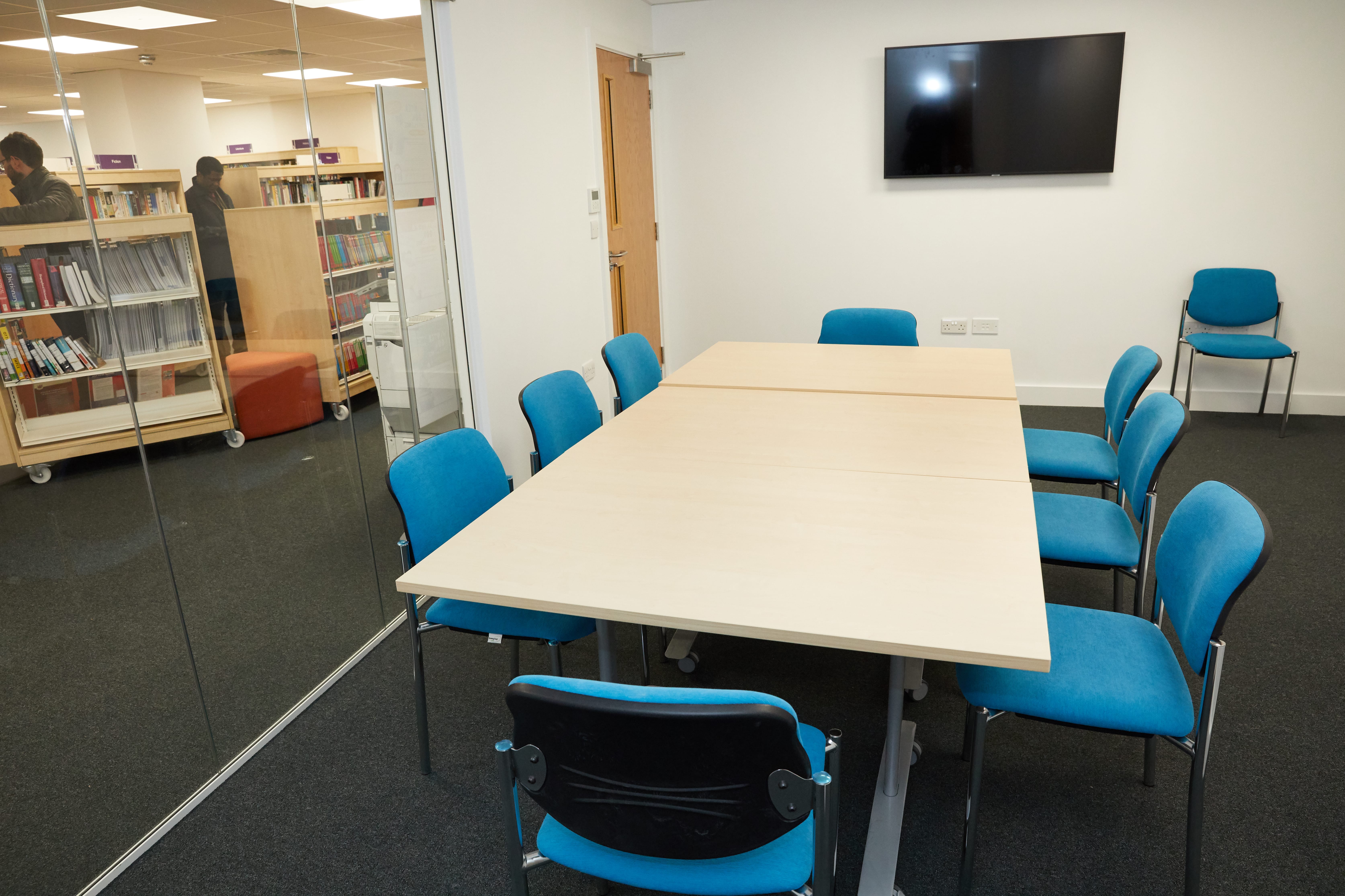 Modern meeting room with large table and blue chairs for collaborative events.