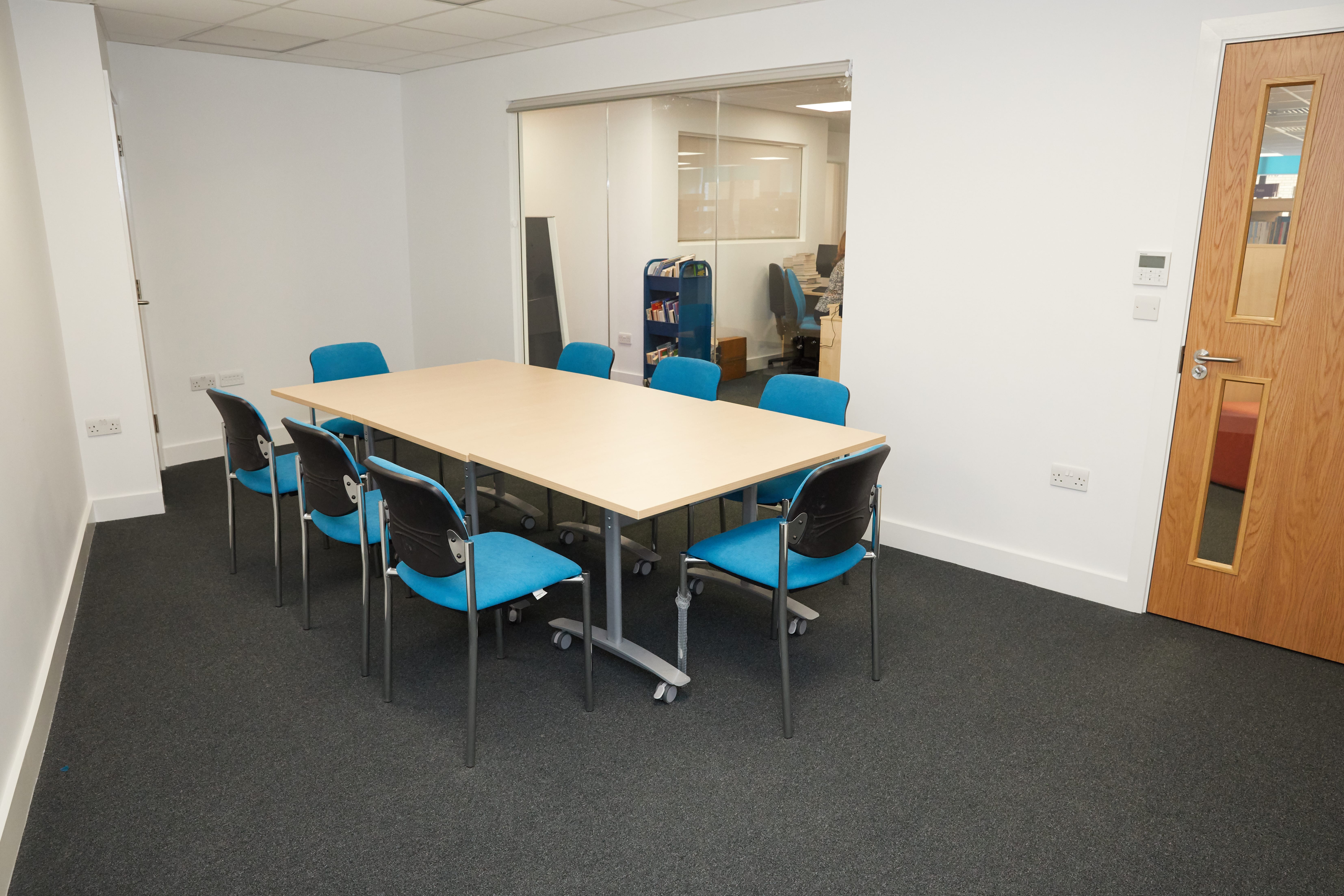 Modern meeting room with blue chairs at Grove Vale Library for collaborative discussions.