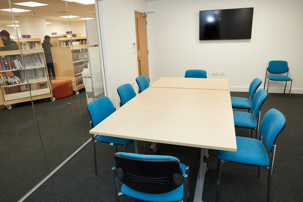 Modern meeting room at Grove Vale Library with large table and blue chairs for presentations.