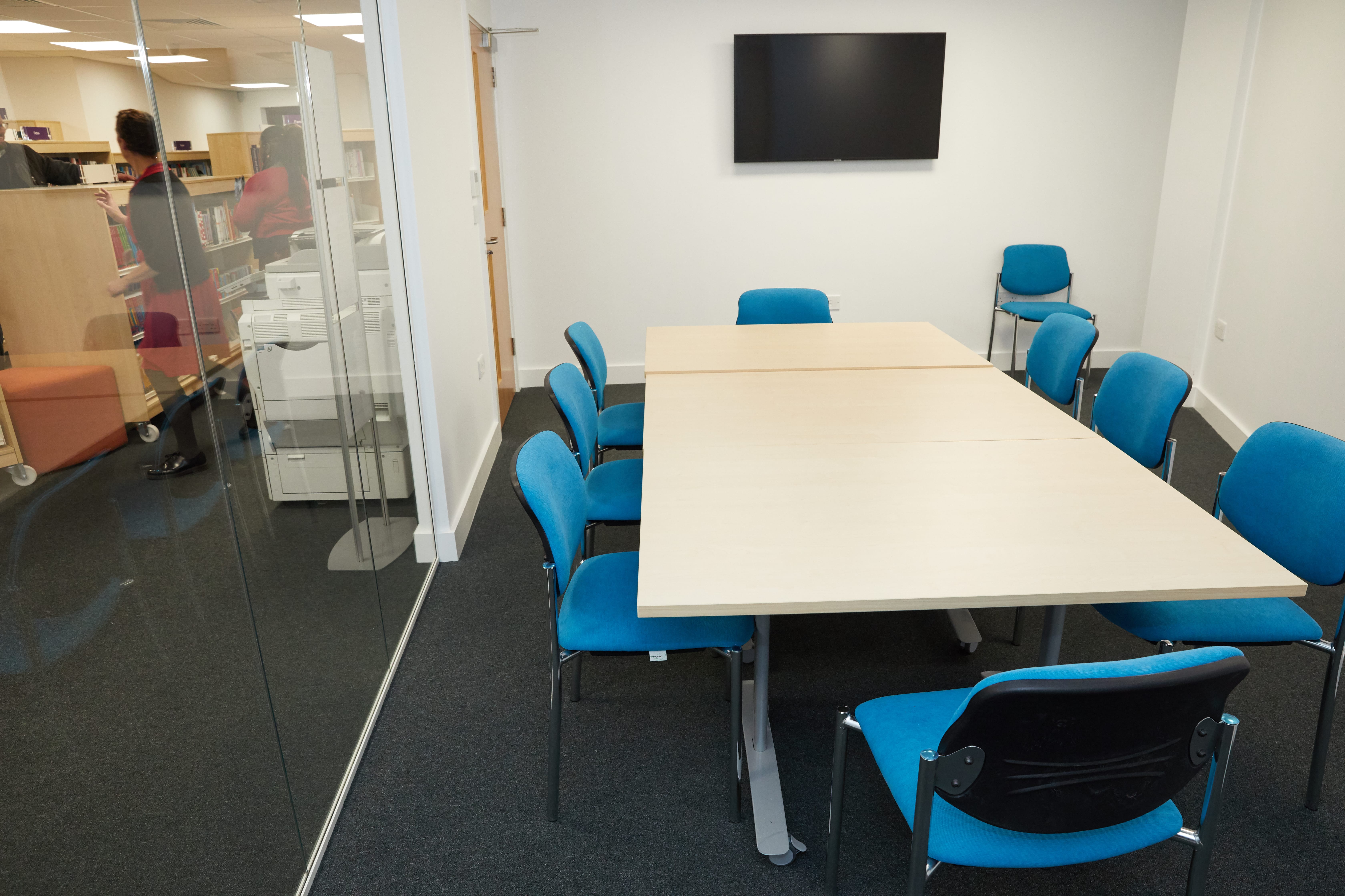 Modern meeting room at Grove Vale Library with large table and blue chairs for presentations.