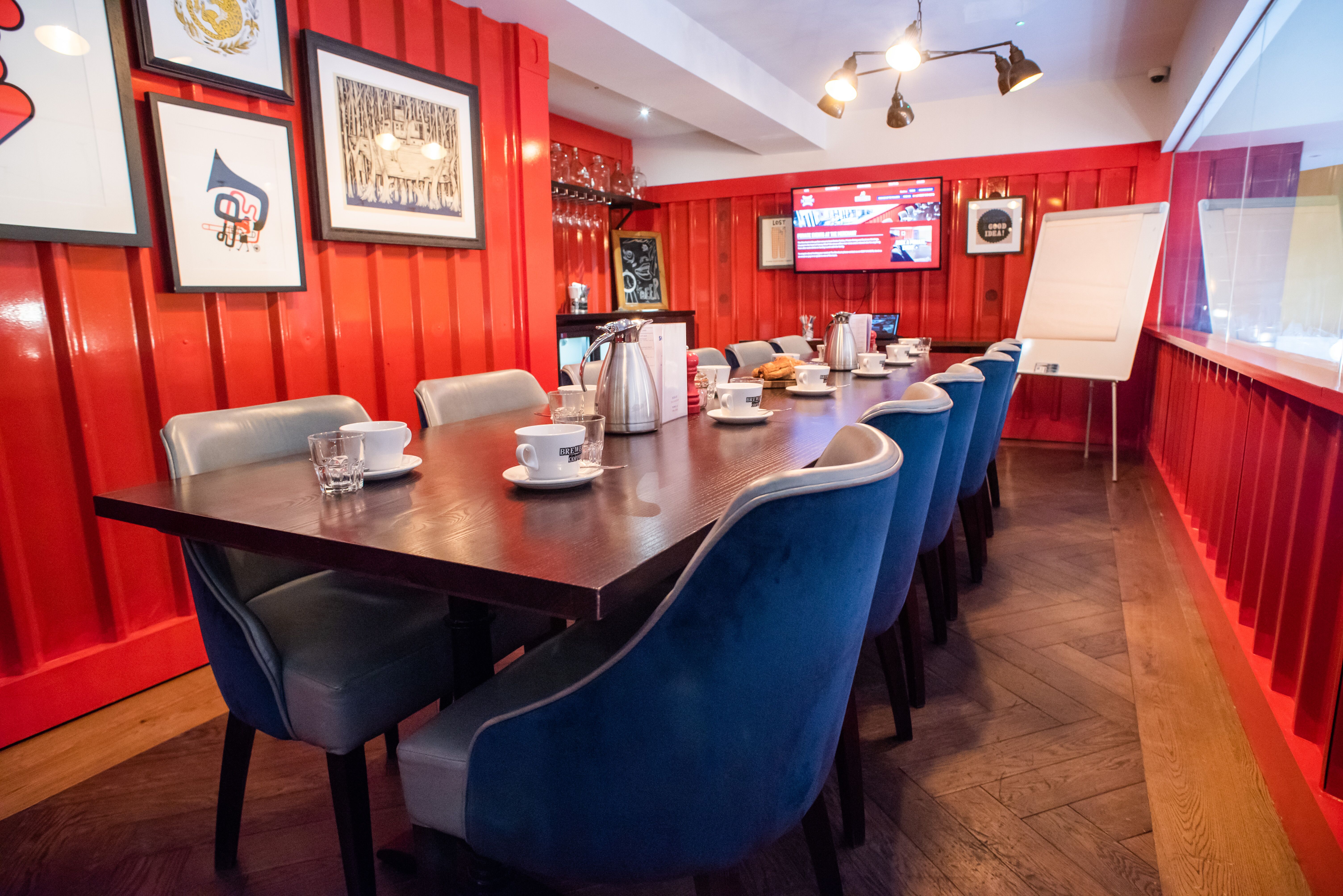 Intimate meeting room with red walls, blue chairs, ideal for collaboration and presentations.