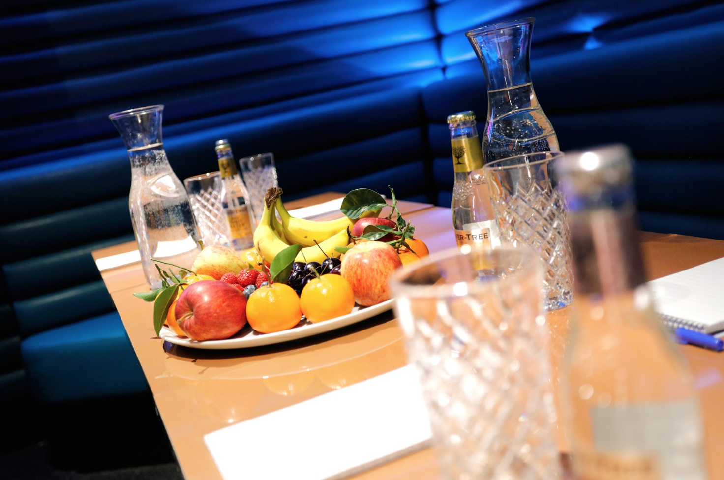 Bar area meeting setup with polished table, fresh fruit, and water carafes at Lucky Voice Holborn.
