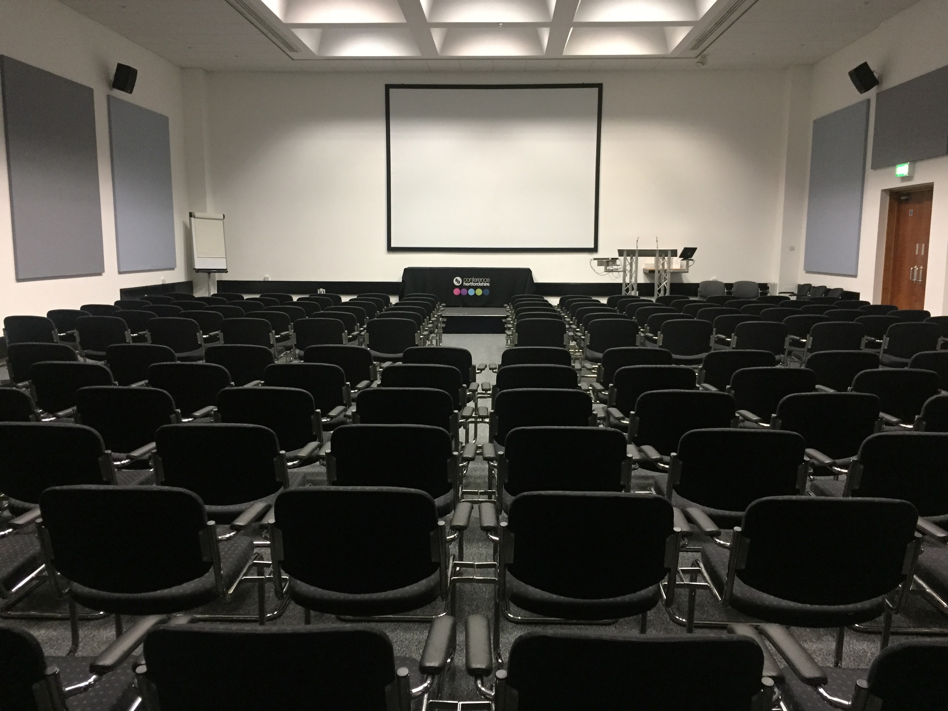 Conference room with black chairs and large screen for presentations and meetings.