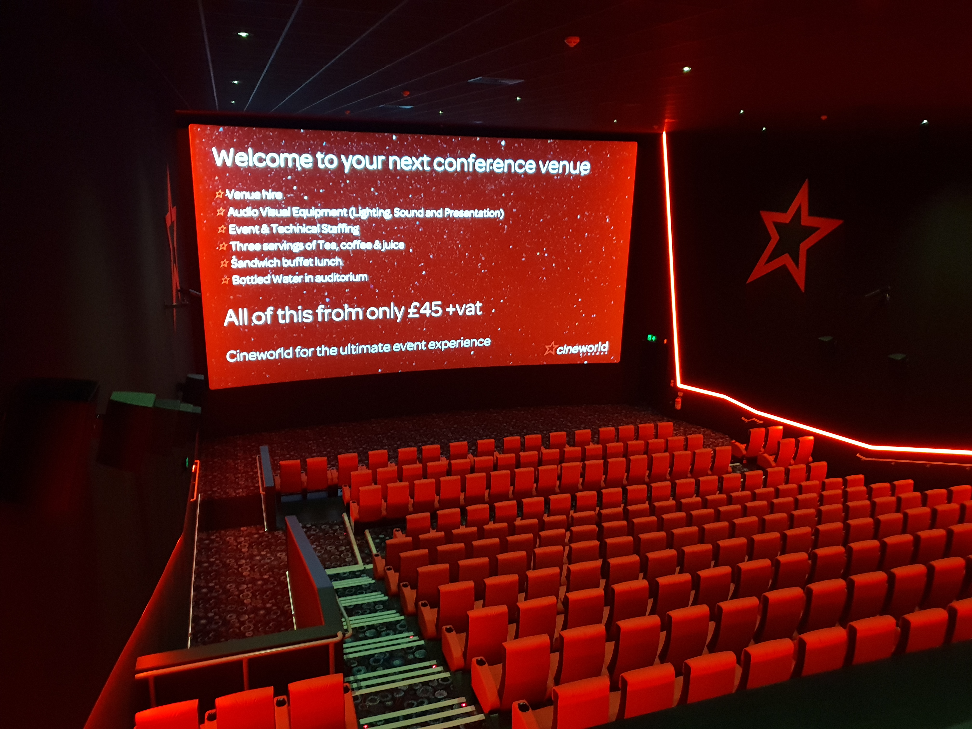 Modern conference venue with red seating and large screen for corporate events.