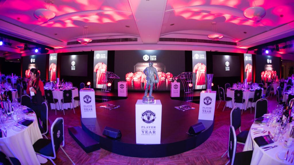 "Elegant event setup at Manchester United for an awards ceremony with dramatic lighting."