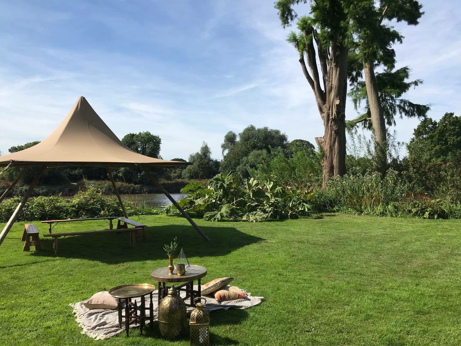 Outdoor event space with stylish tent and lush greenery at Secret River Garden.