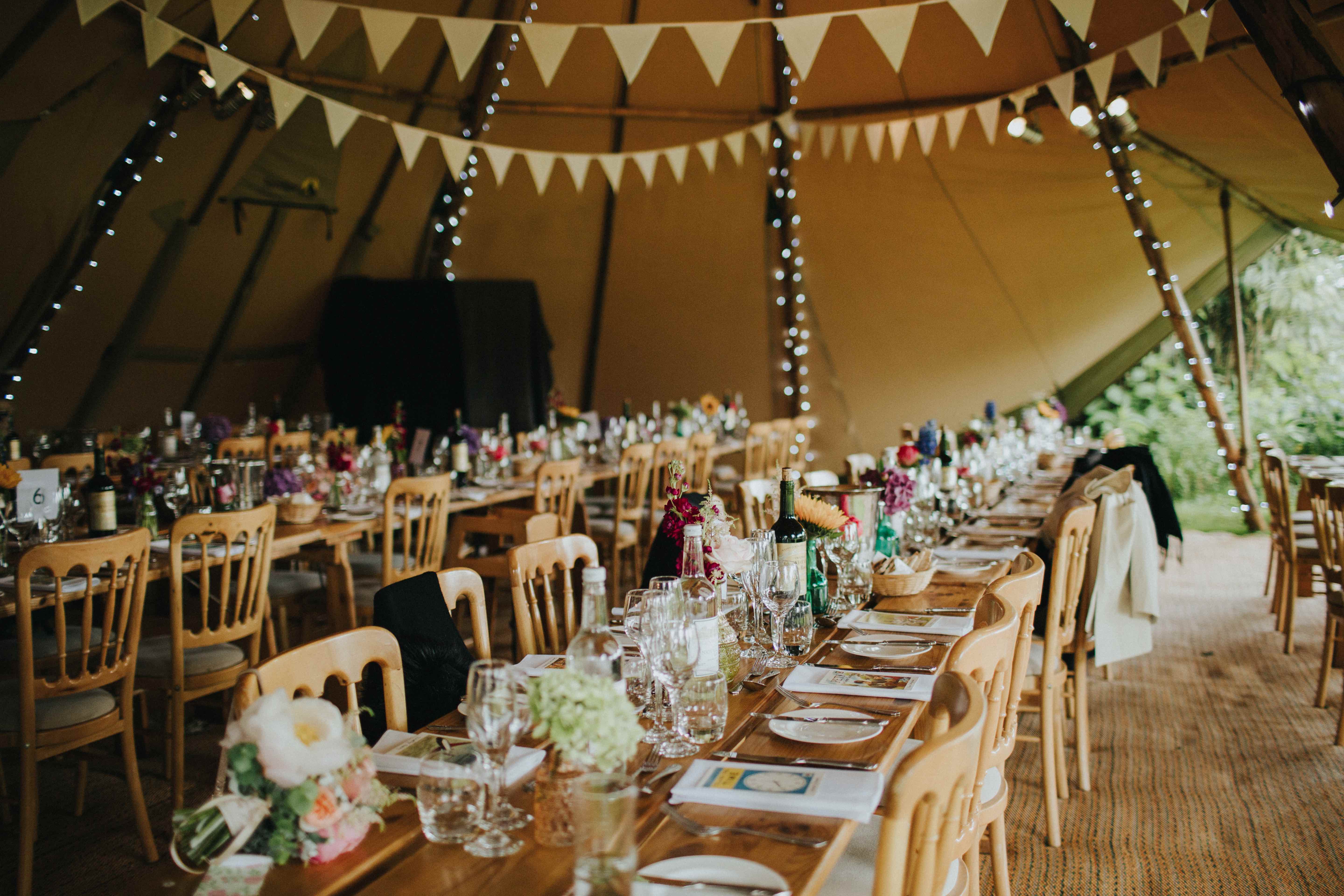 Elegant tented event space with wooden tables, perfect for weddings and outdoor gatherings.