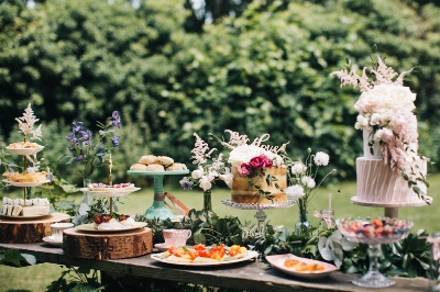 Outdoor dessert table with cakes and pastries for weddings and garden parties.
