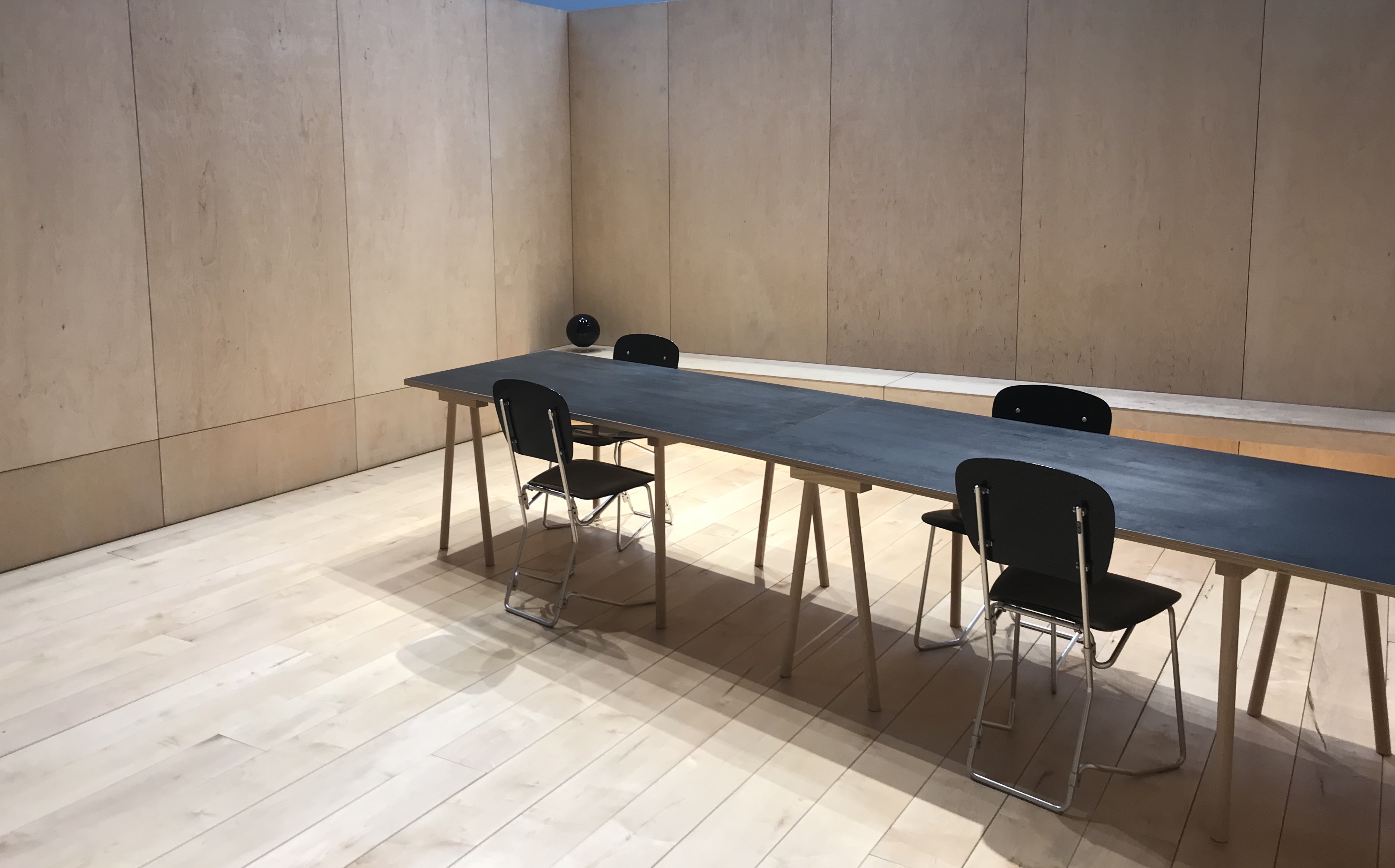 Minimalist meeting room with dark table and black chairs, ideal for corporate events.
