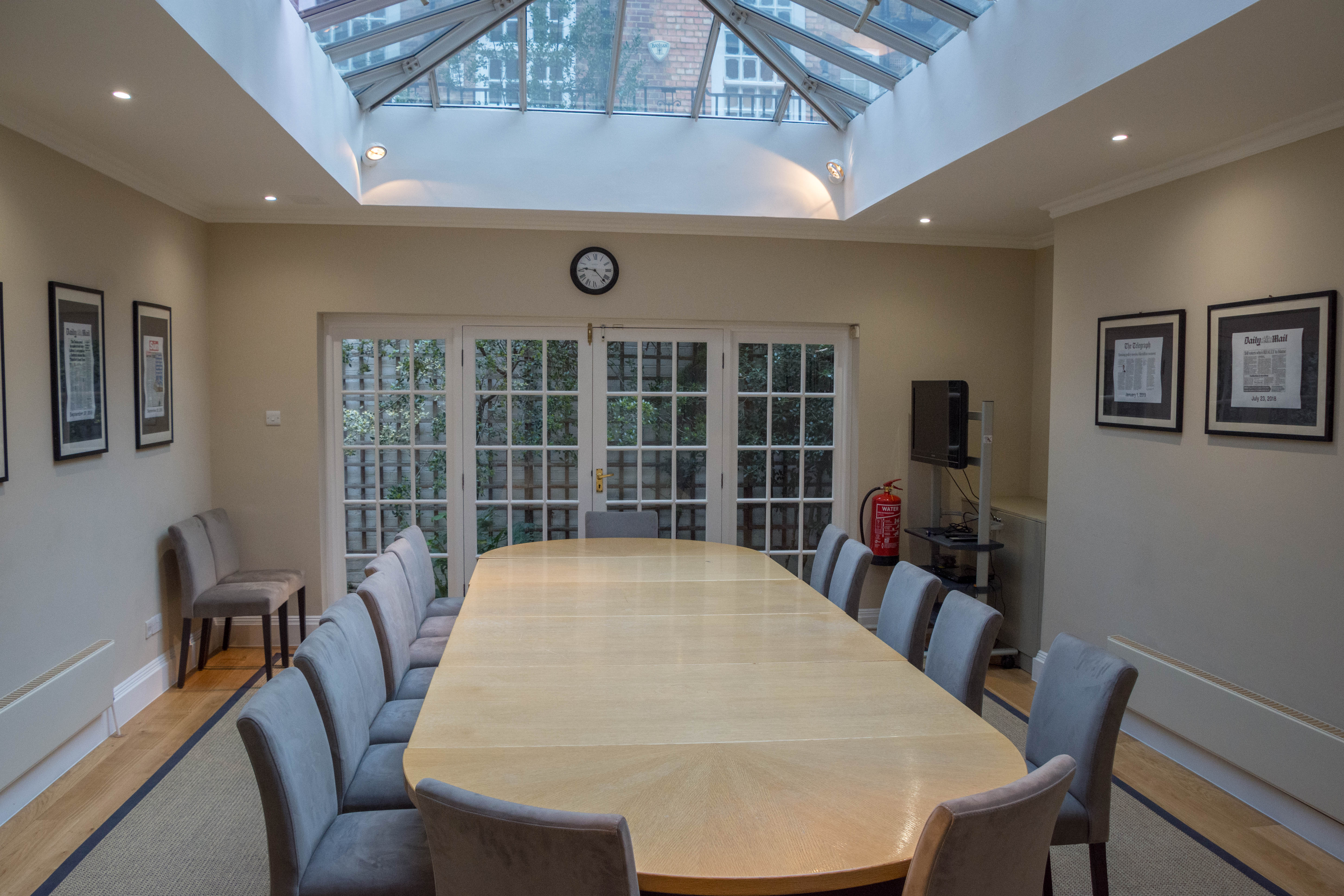 Boardroom with wooden table and skylight, ideal for meetings and workshops.