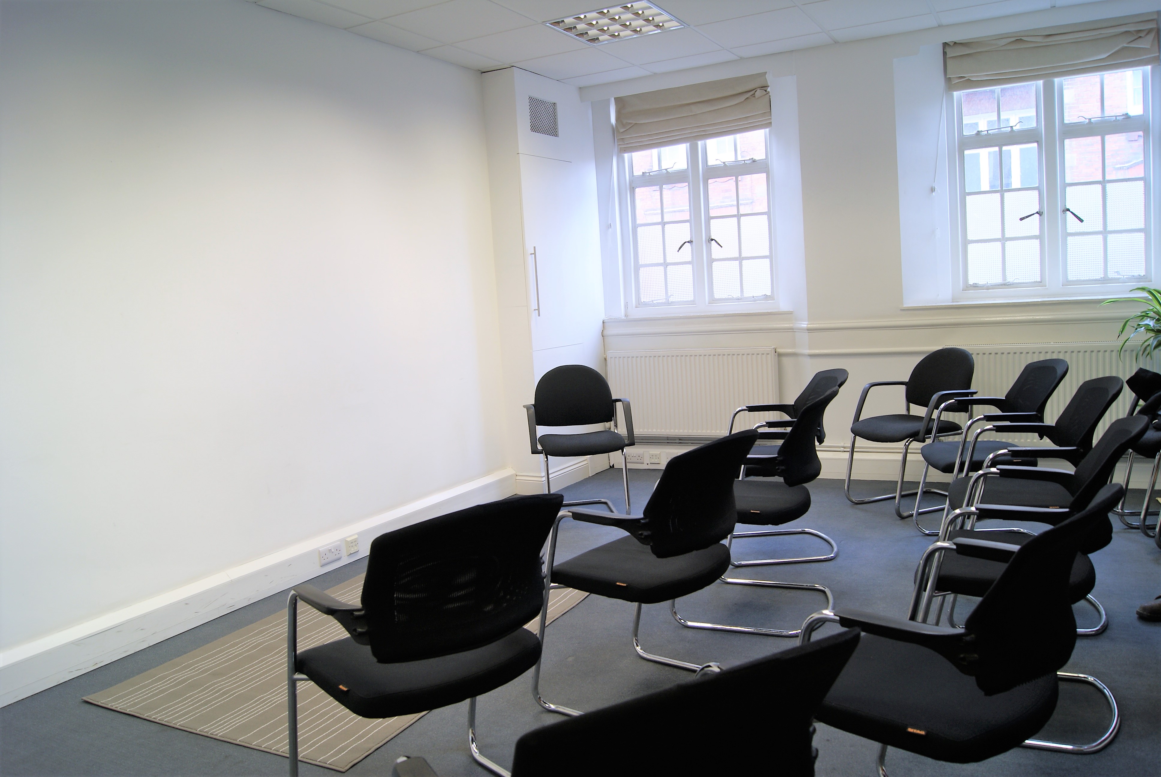 Minimalist meeting room in Marylebone with black chairs for workshops and discussions.