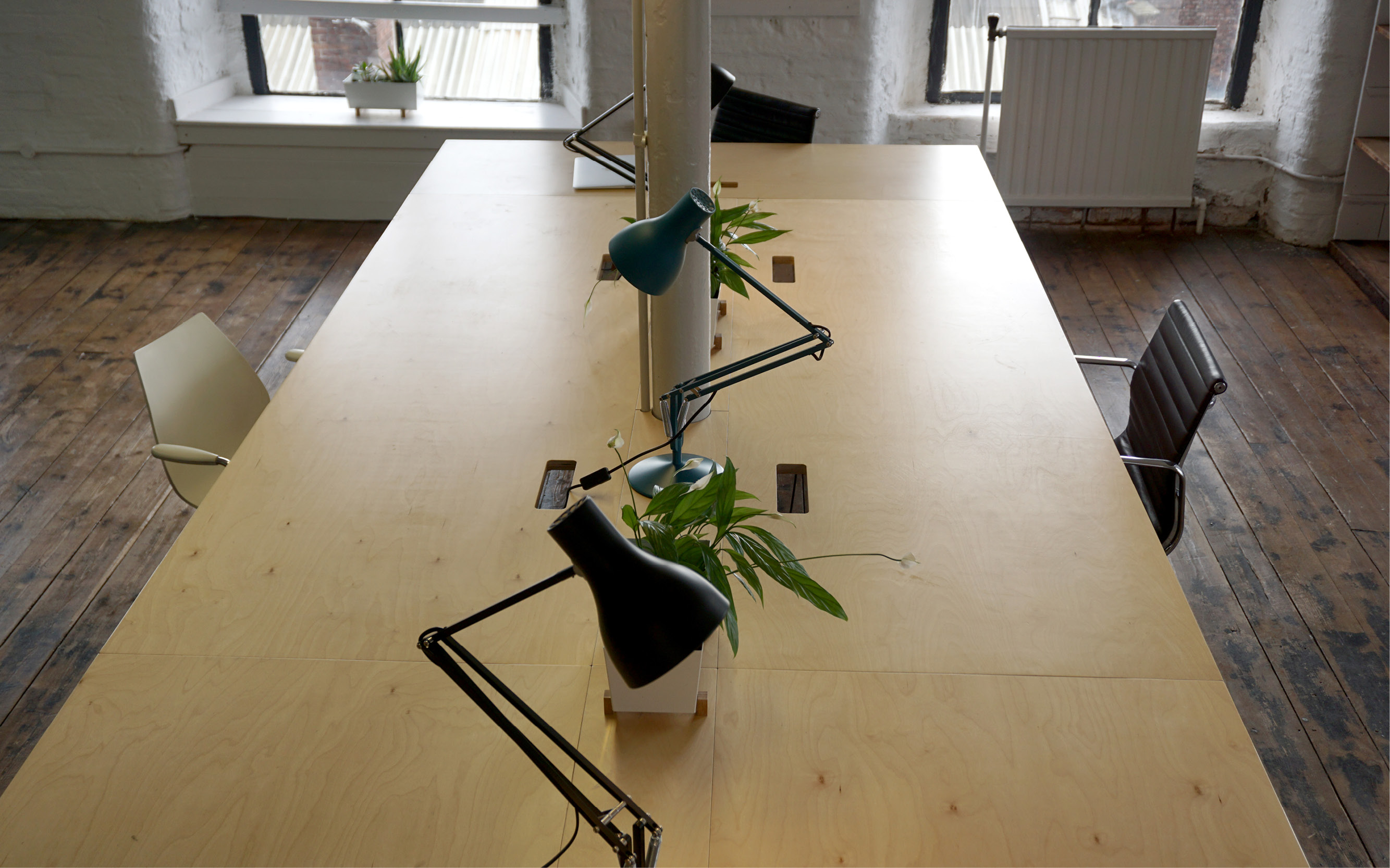 Modern minimalist meeting space with wooden table, ideal for workshops and brainstorming.