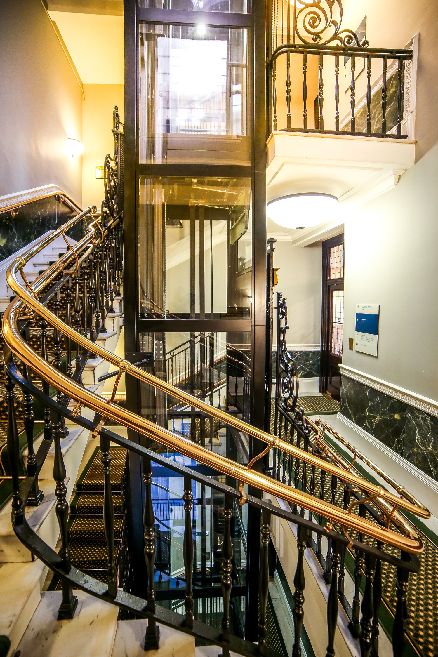 Elegant staircase with glass elevator at Trafalgar Rooms, perfect for upscale events.