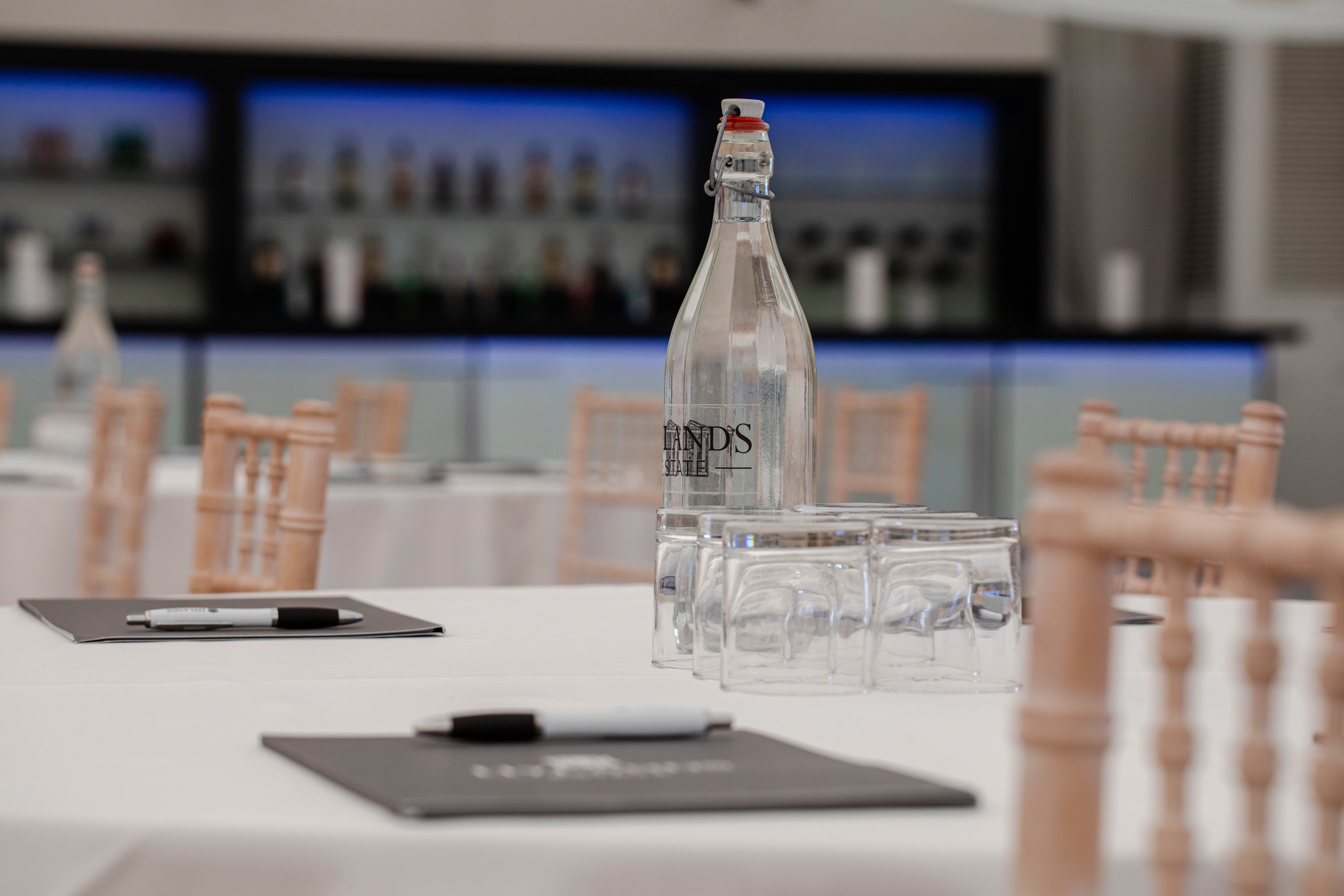 Grand Pavilion meeting setup with white linens, water bottles, and notepads for events.