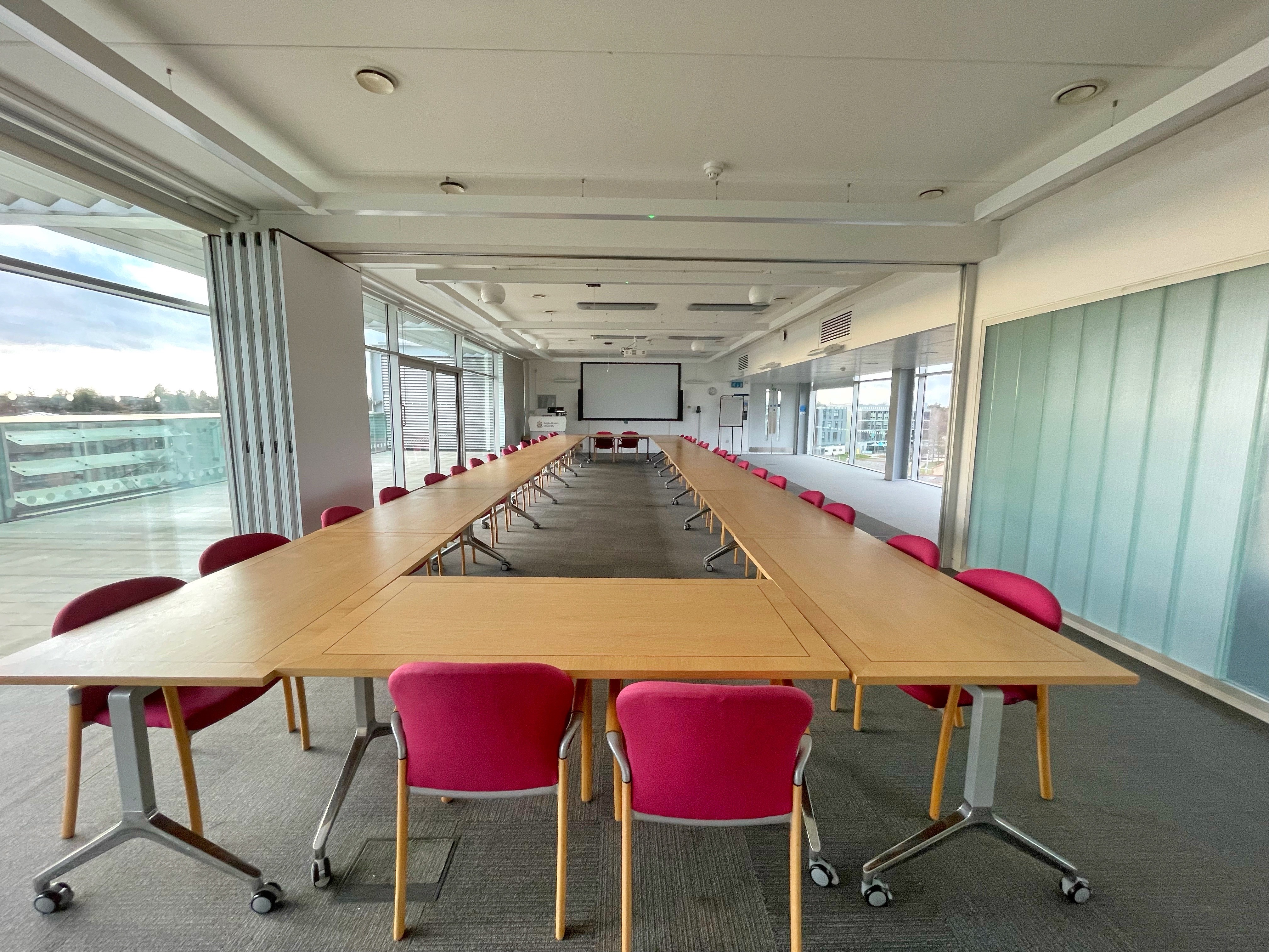 Spacious MAB 404 meeting room with pink chairs, ideal for workshops and strategic planning.