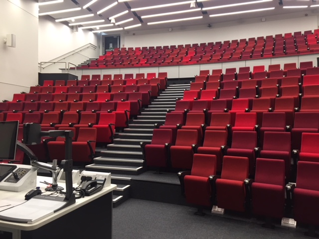 Modern auditorium with tiered red seating for presentations at ARU Venue Hire, Cambridge.