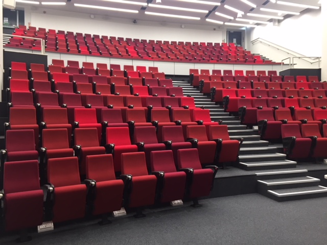 Modern auditorium with tiered red seating for presentations and conferences in Cambridge.