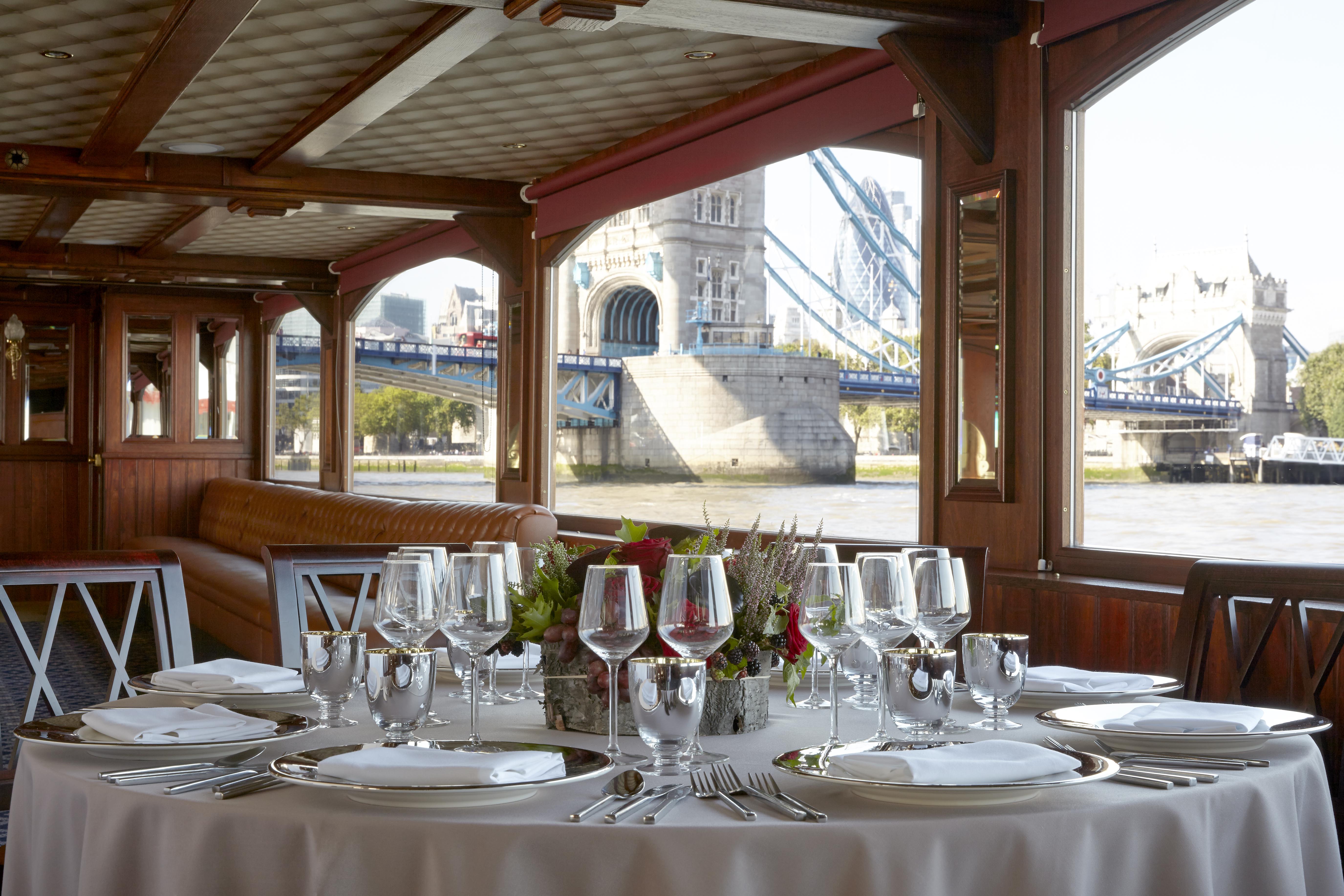 Elegant dining table on a boat with Tower Bridge view, perfect for upscale events.