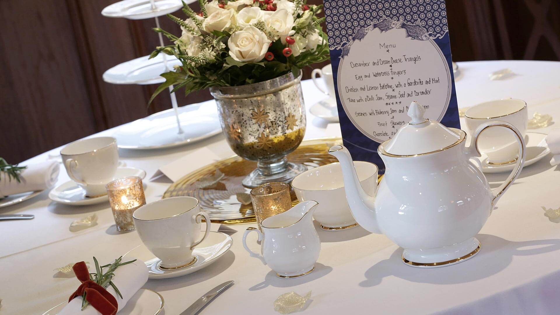 Elegant tea event table with fine china and floral centerpiece in Edwardian venue.