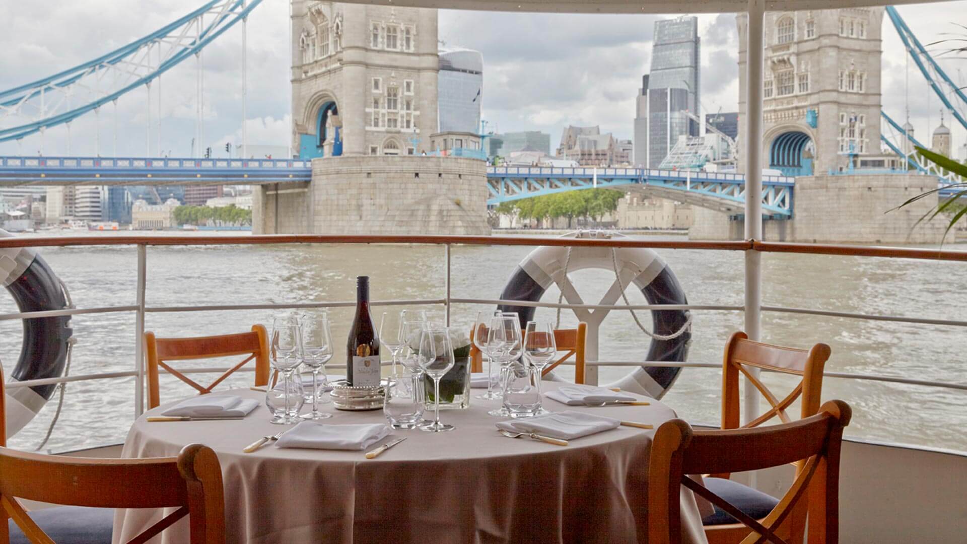 Elegant dining table on a boat with Tower Bridge, perfect for upscale events and dinner cruises.