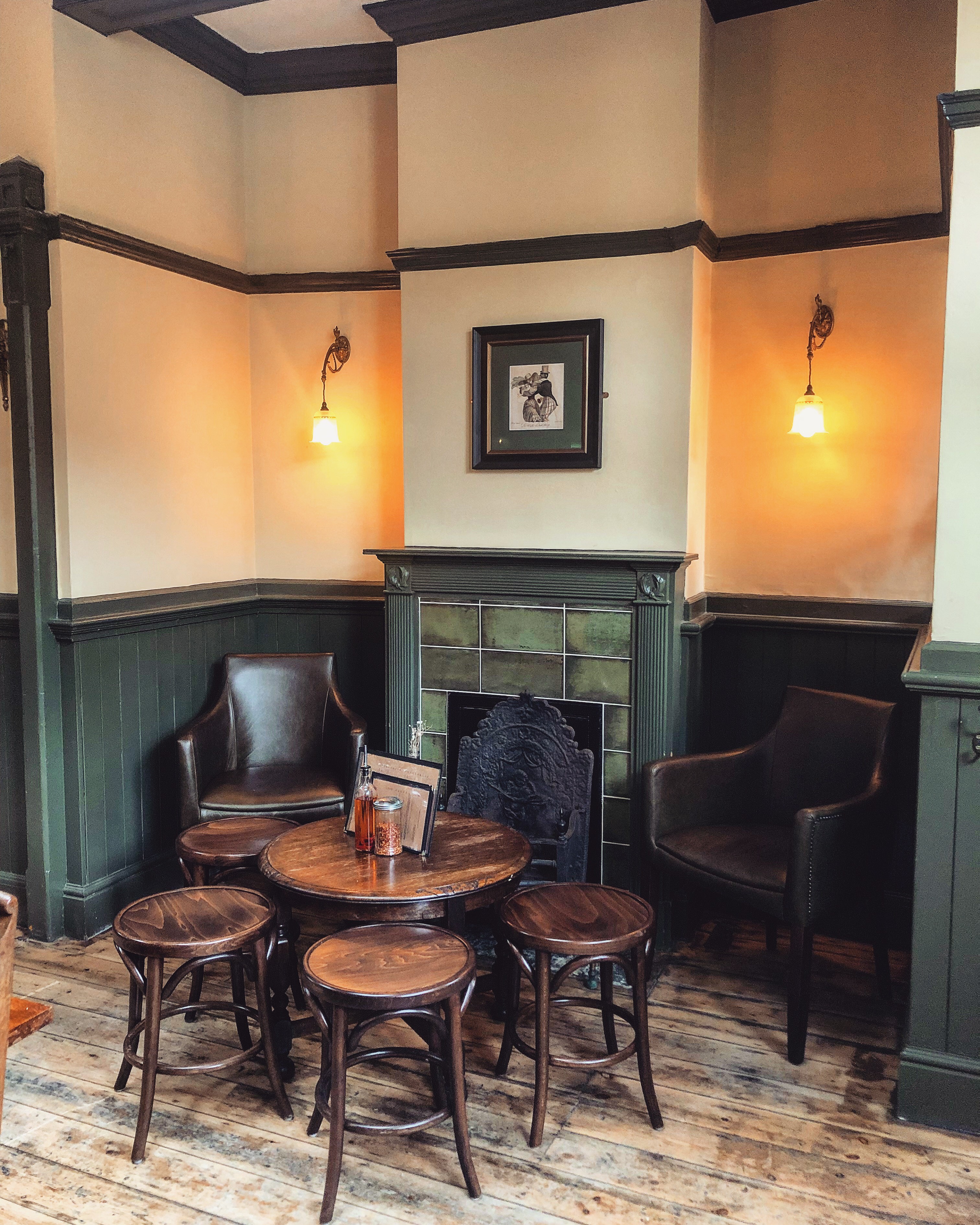 Cozy corner with armchairs and fireplace at The George and Monkey for networking events.