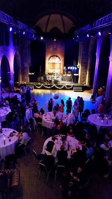 Vibrant Roxy Central event space with round tables, live band, and festive ambiance.