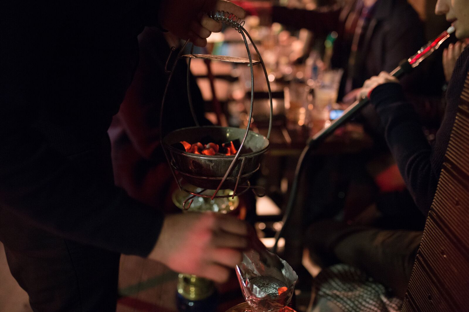 Cozy Maddox Club Mayfair garden with server preparing hookah for social events.