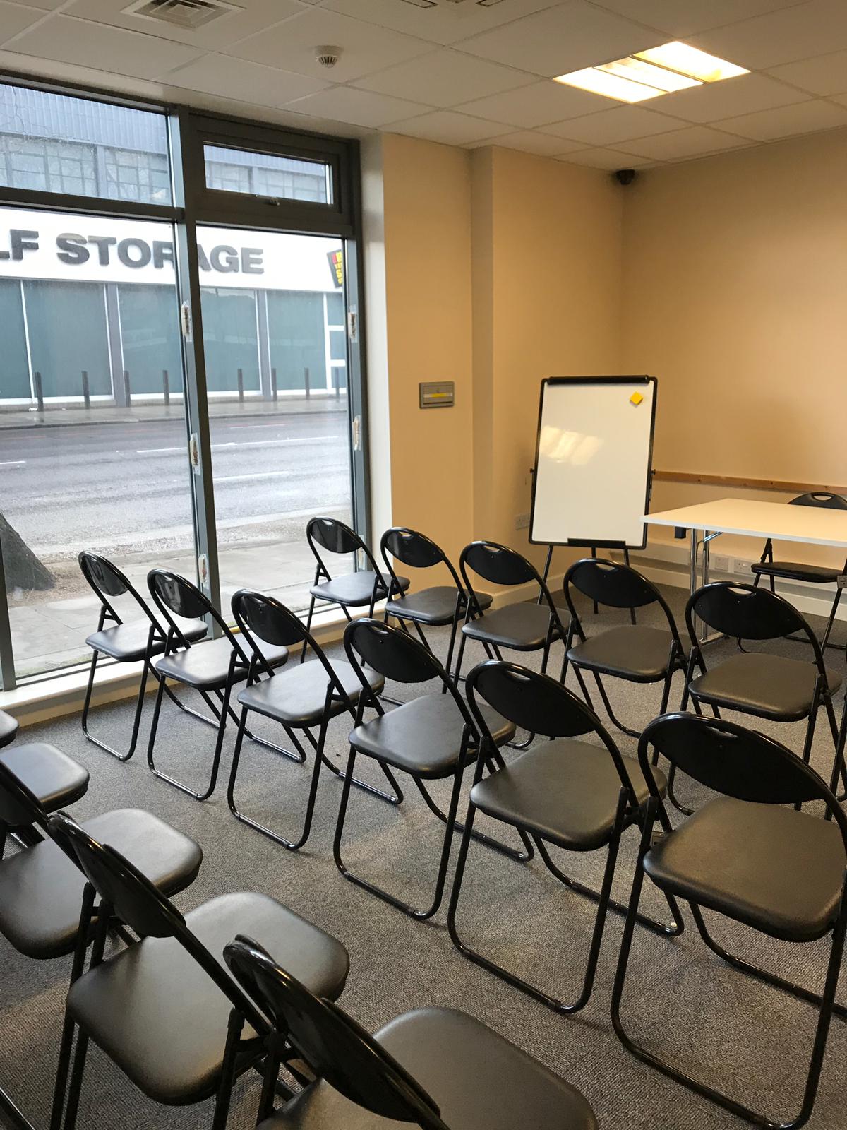 Conference hall with black chairs and whiteboard, ideal for workshops and meetings.
