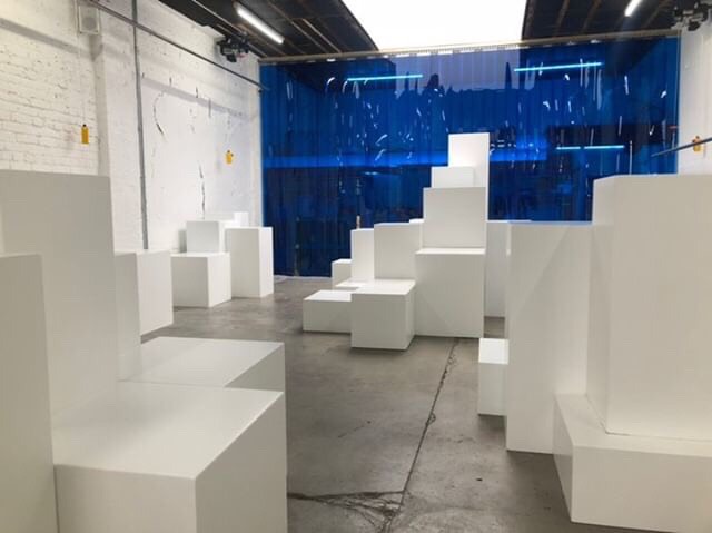 Modern minimalist event space with geometric seating and blue drapery for versatile events.