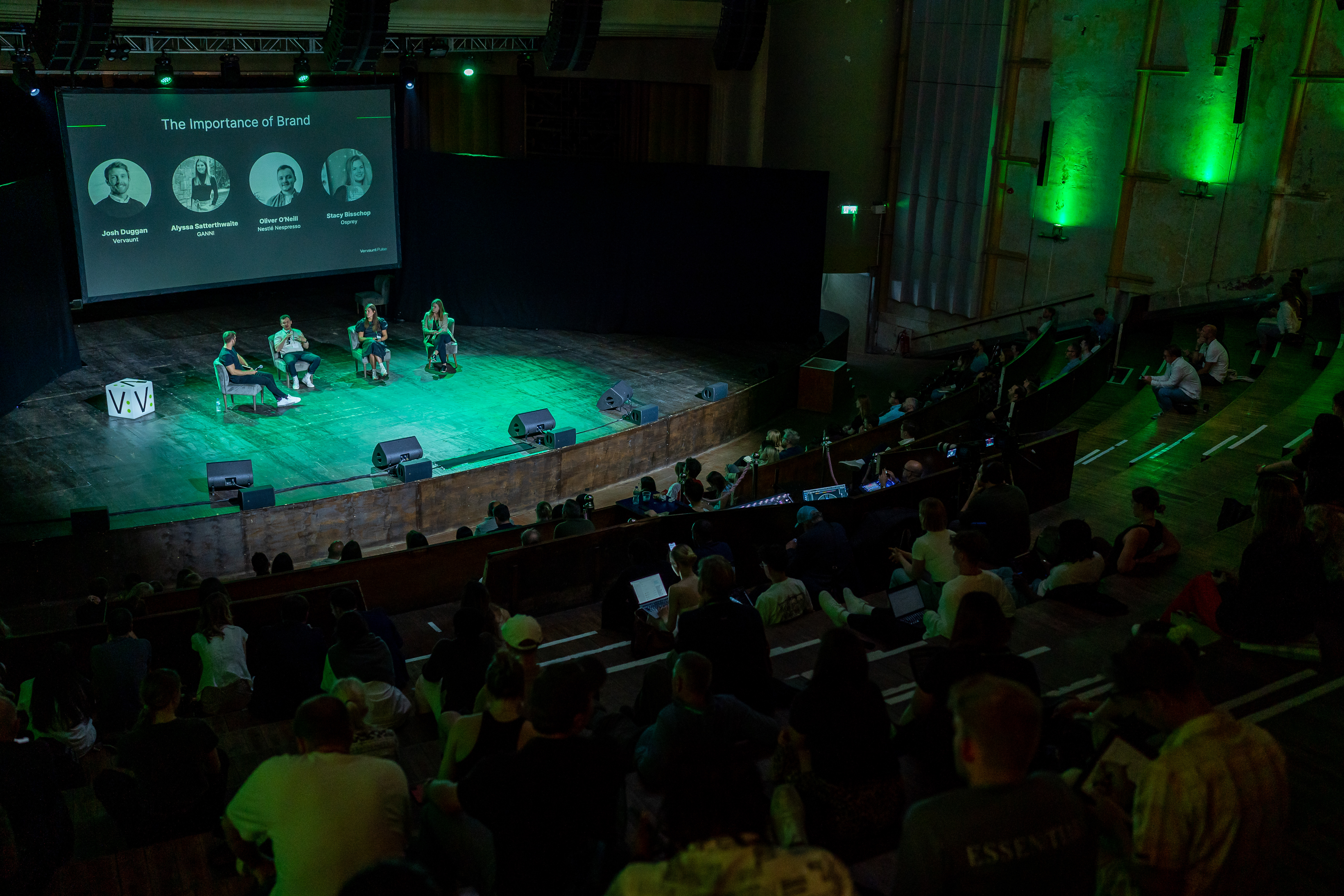 Panel discussion on branding in EartH Theatre with green-lit stage and tiered seating.