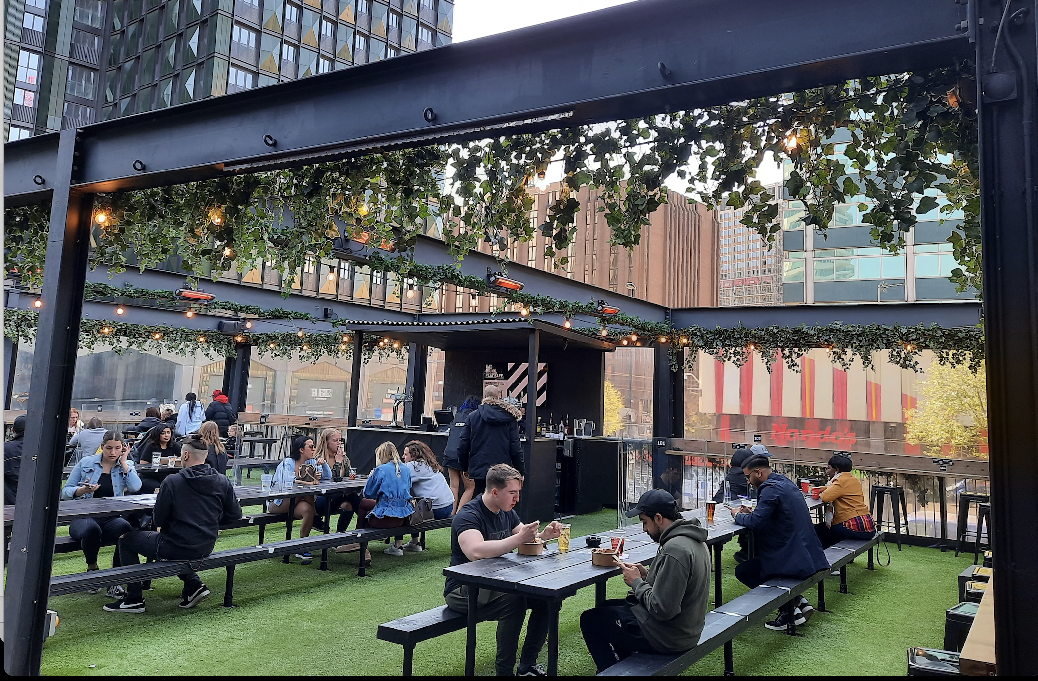 Vibrant outdoor event space at Boxpark Croydon with communal seating and greenery.