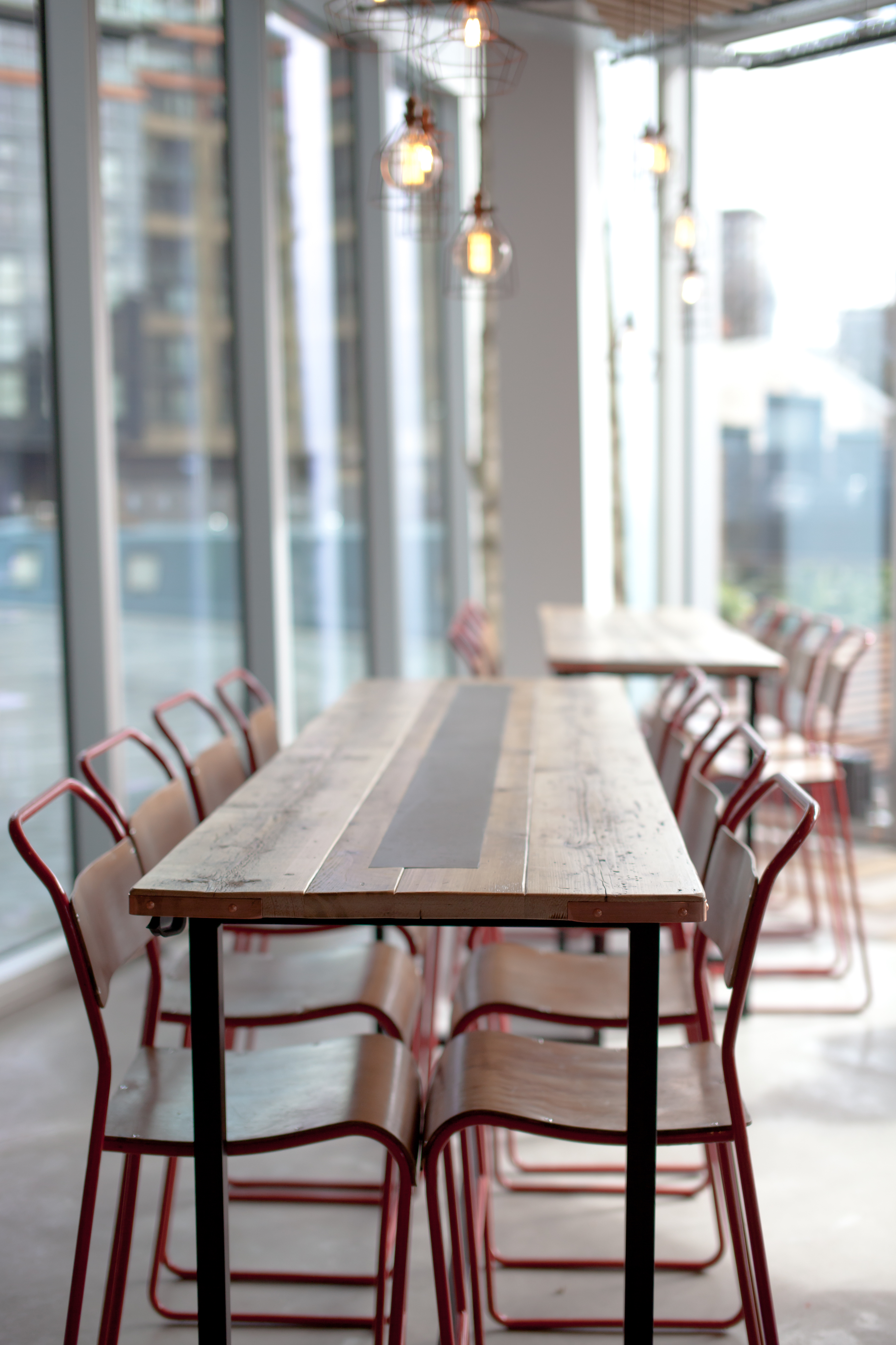 Modern meeting space with wooden table and red chairs, perfect for collaboration events.