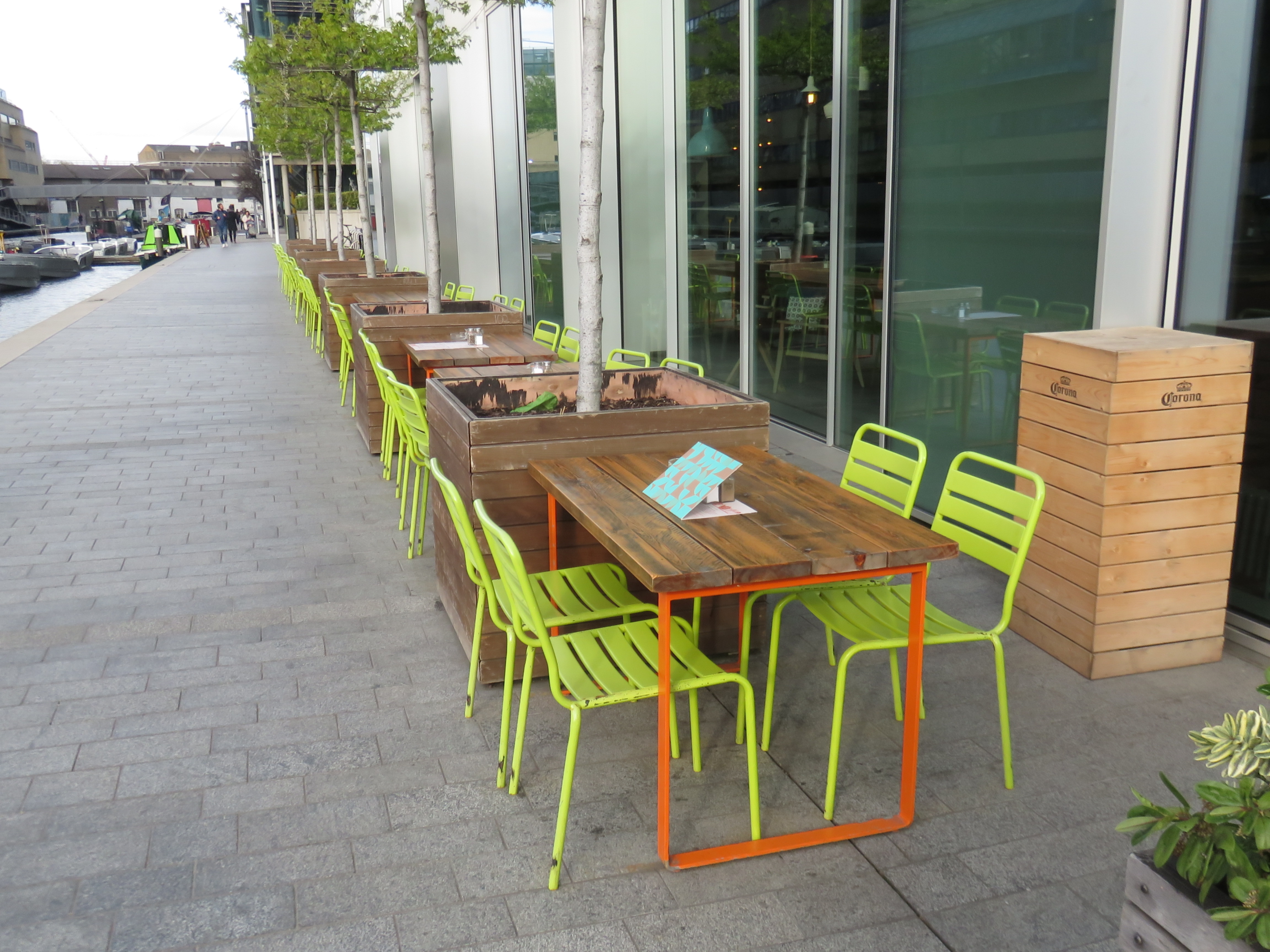 Outdoor seating at KuPP Bar with green chairs, ideal for networking events by the water.