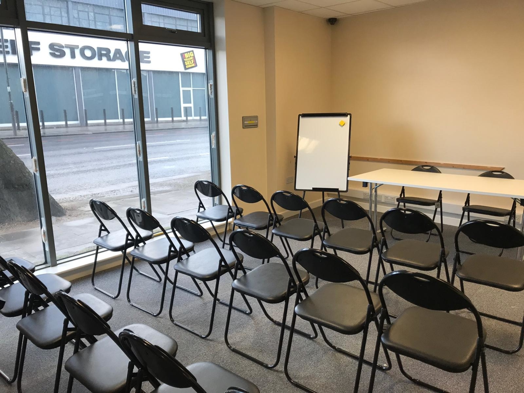 Simple meeting room in Whitechapel, London with black chairs and flip chart.